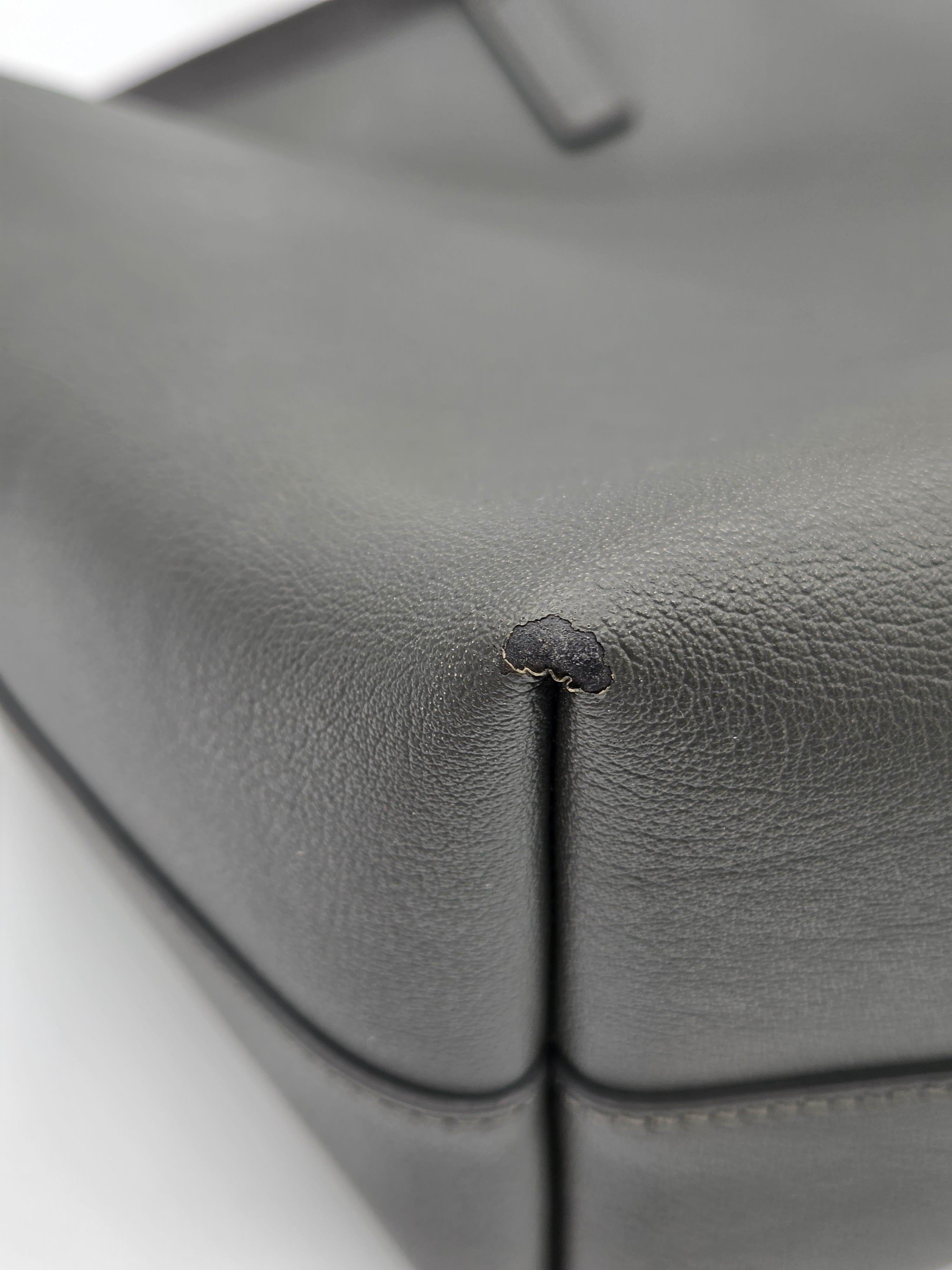 Close-up of a small hole in gray leather upholstery