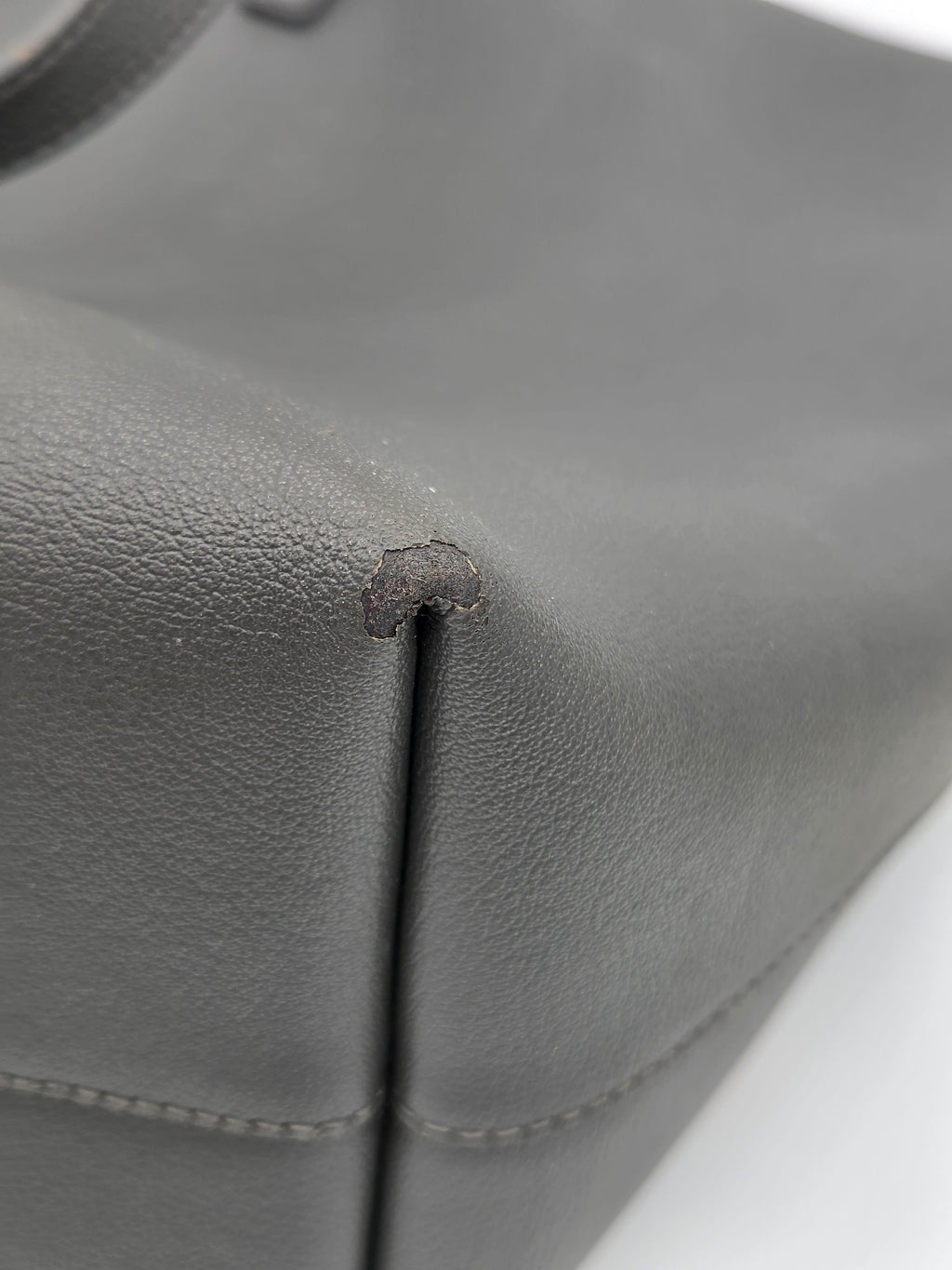 Gray leather car seat with a small tear or defect.
