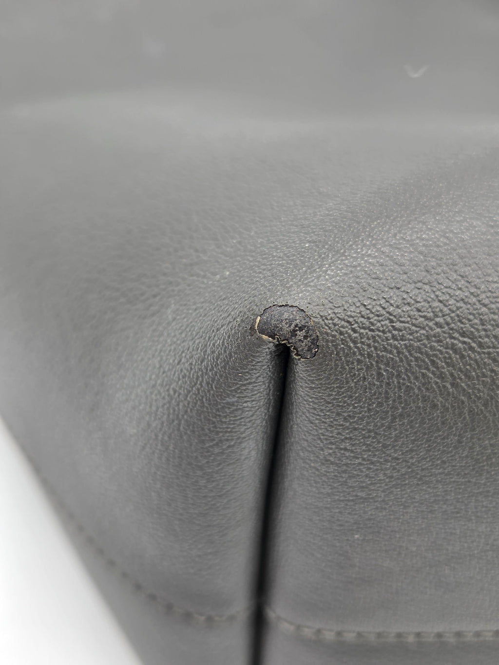 Close-up of a gray leather surface with a small dark spot.