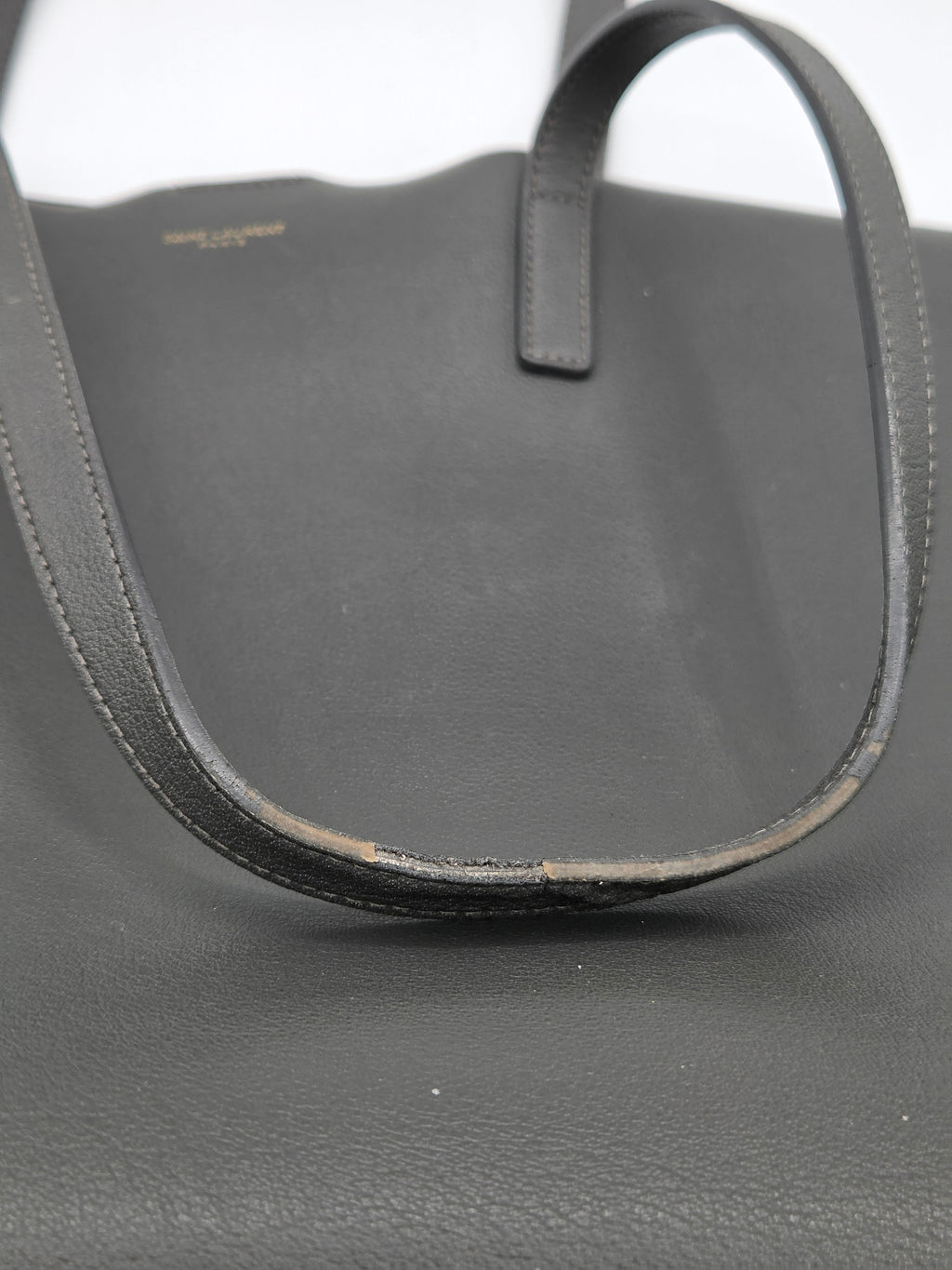 Close-up of a black leather bag with a strap on a white background
