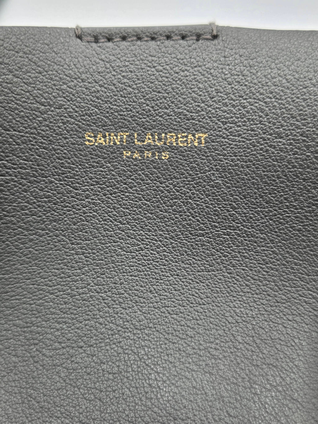 Close-up of a gray leather product with 'Saint Laurent' branding.