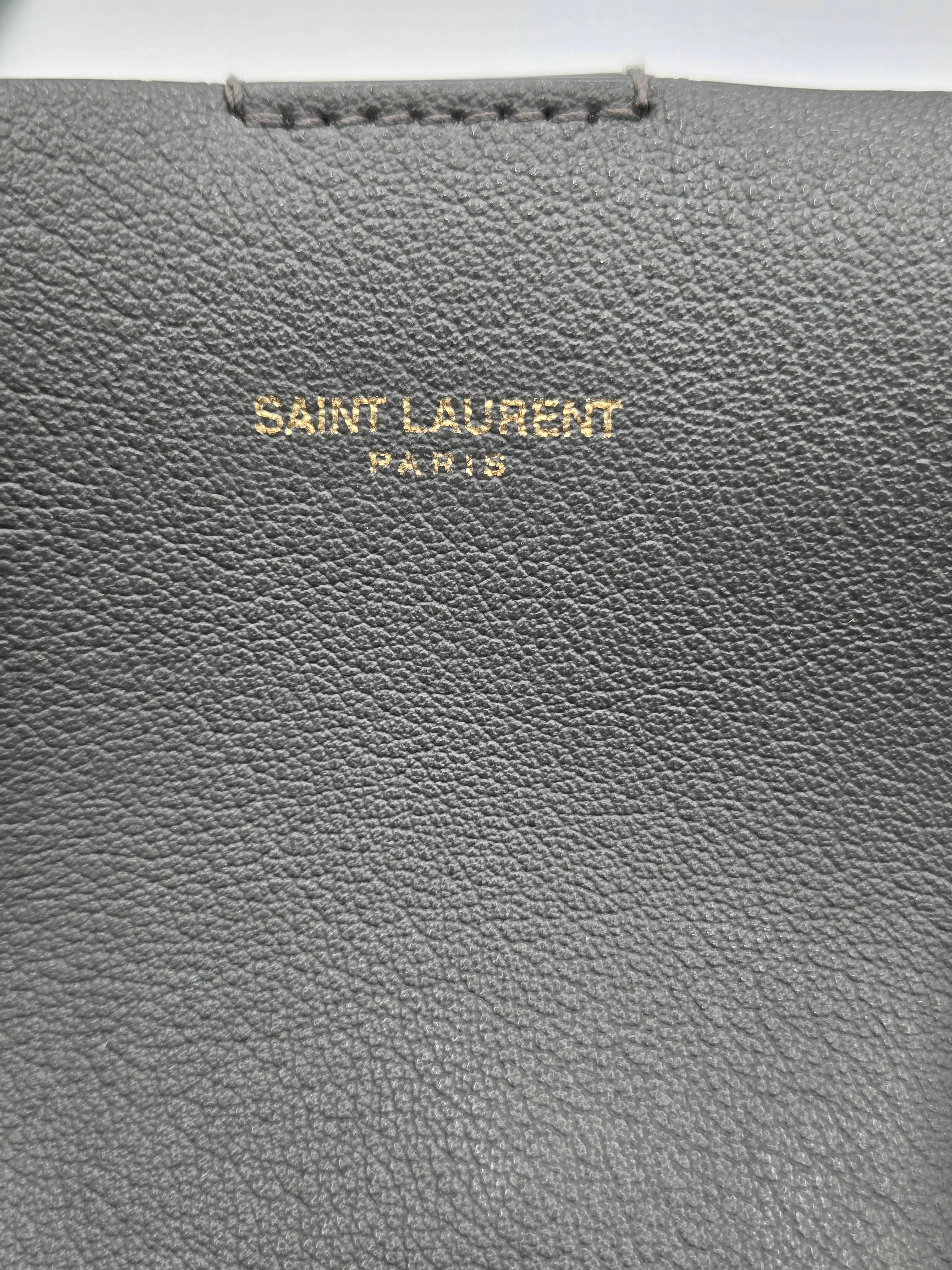 Close-up of a gray leather product with 'Saint Laurent' branding.