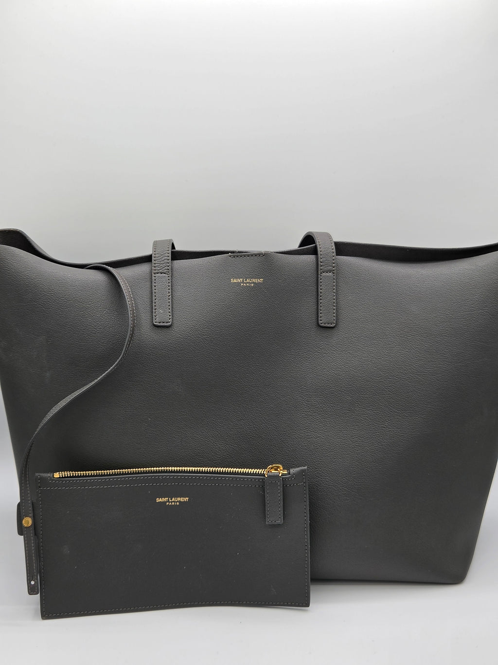 Black leather bag with a smaller pouch on a light gray background