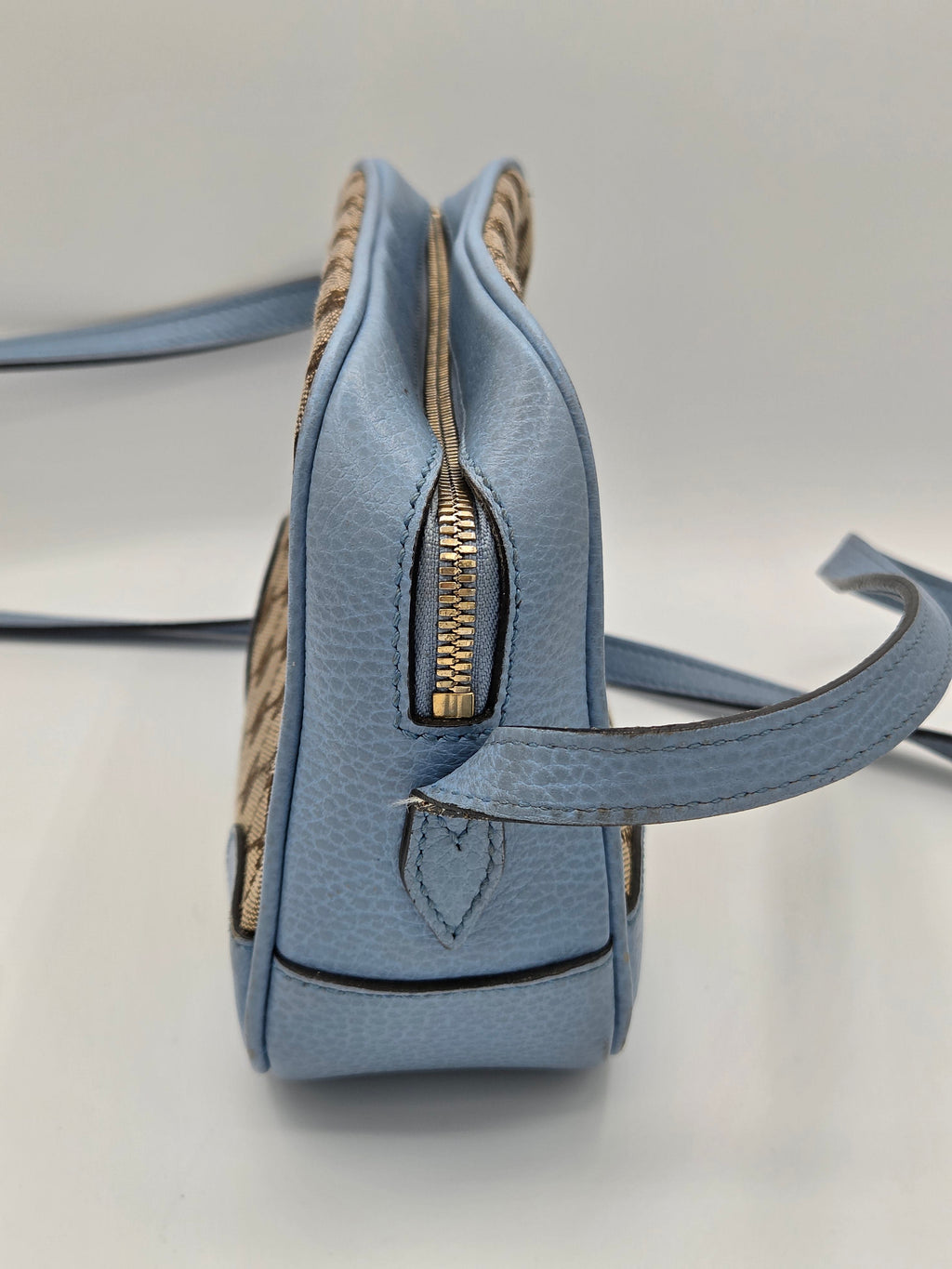 Blue handbag with gold zipper on a light gray background