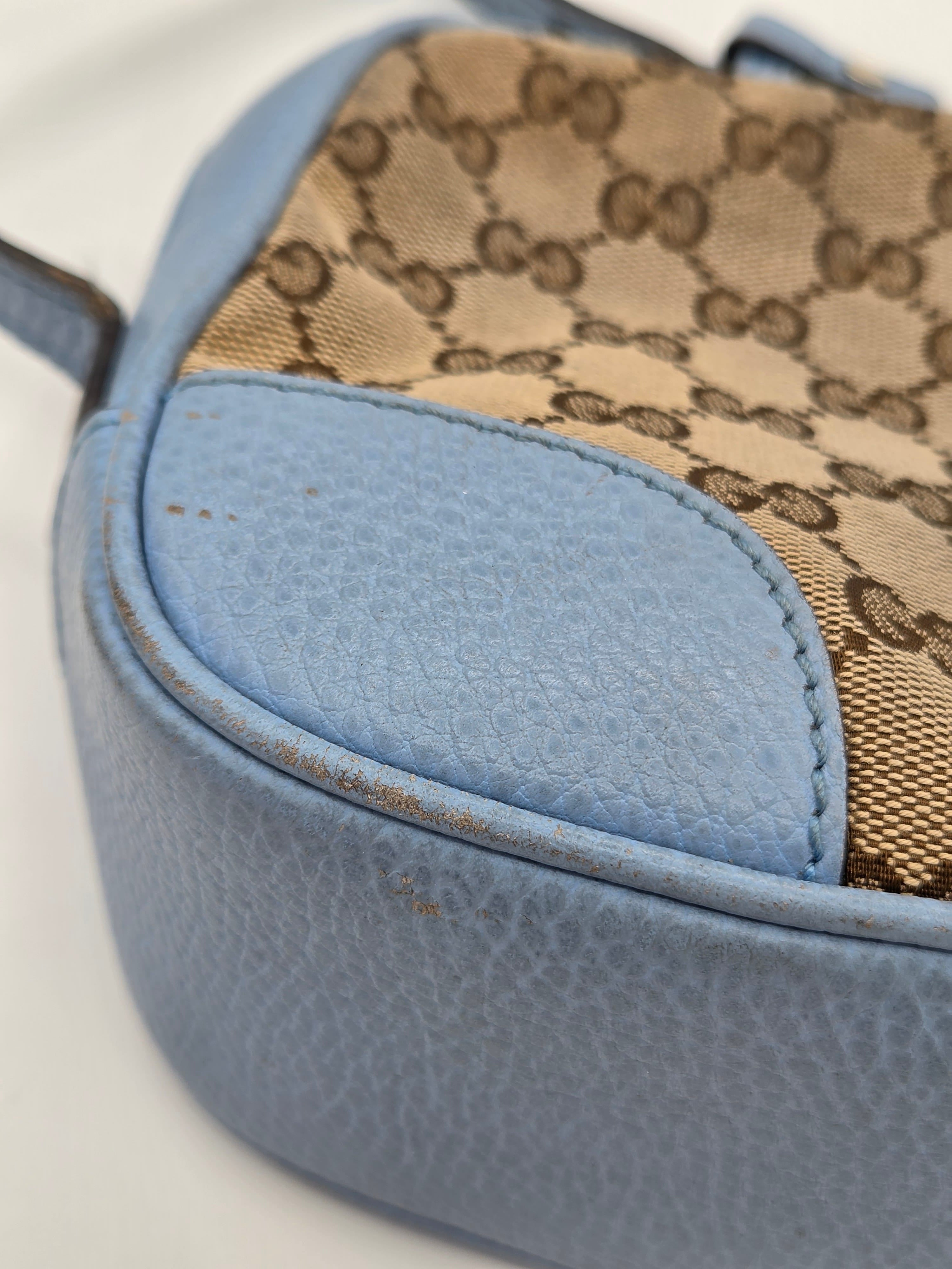 Close-up of a handbag with patterned fabric and blue leather accents on a white background