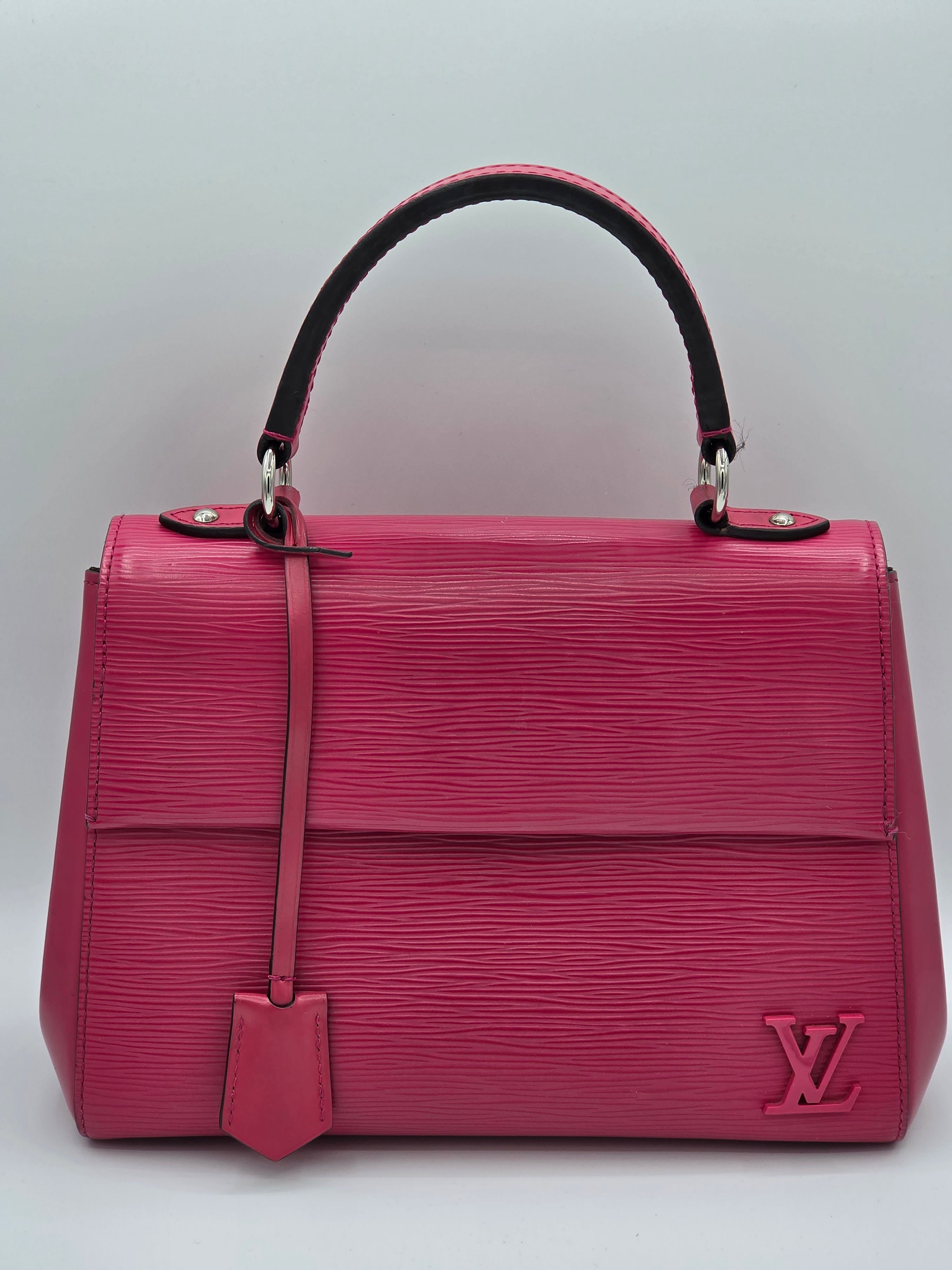 Pink handbag with a brand logo on a light gray background