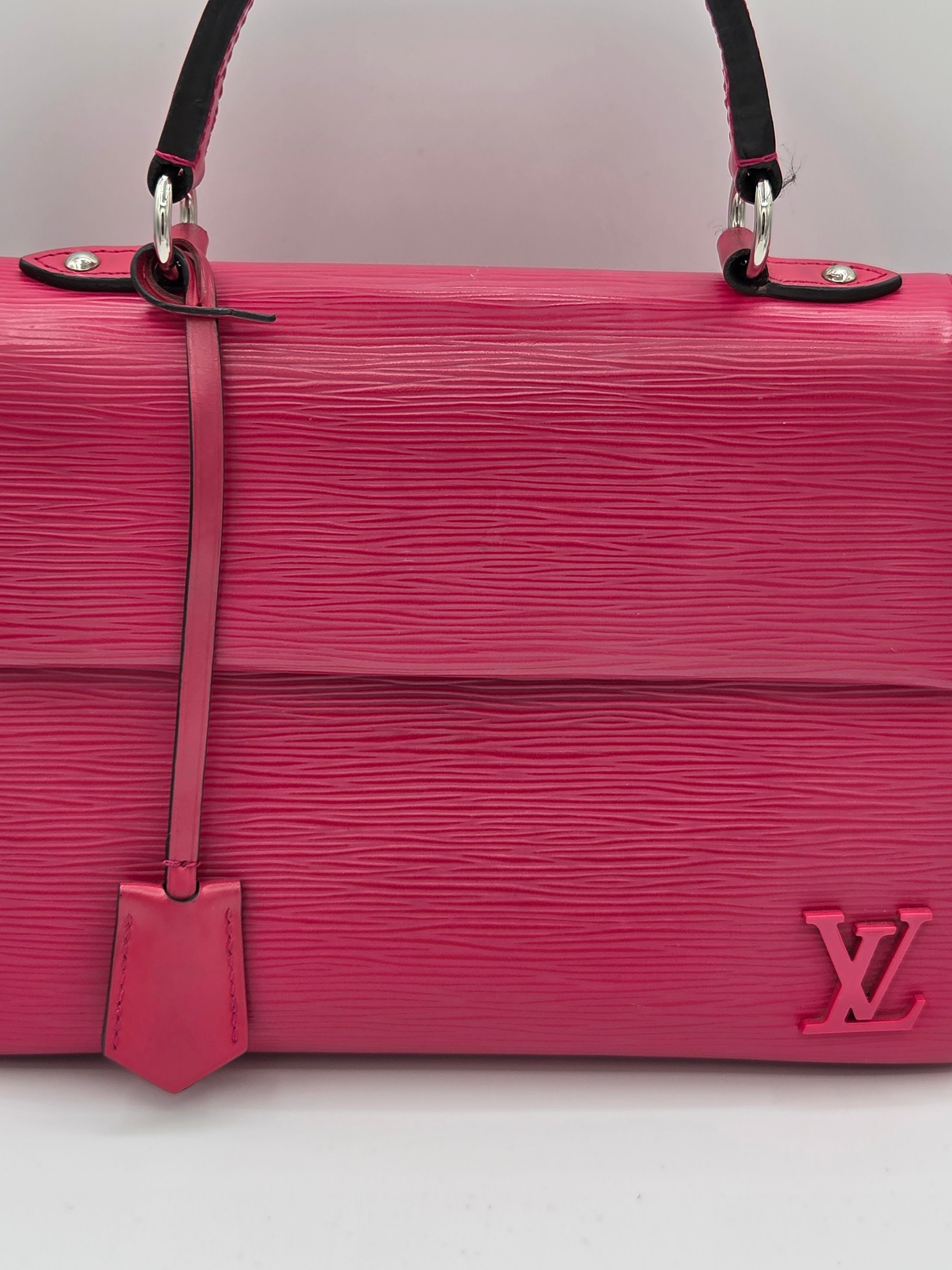 Pink handbag with a visible brand logo on a light gray background