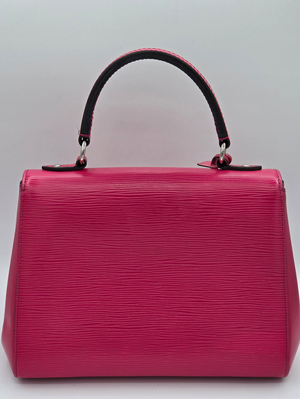 Pink handbag with black handle on a light gray background