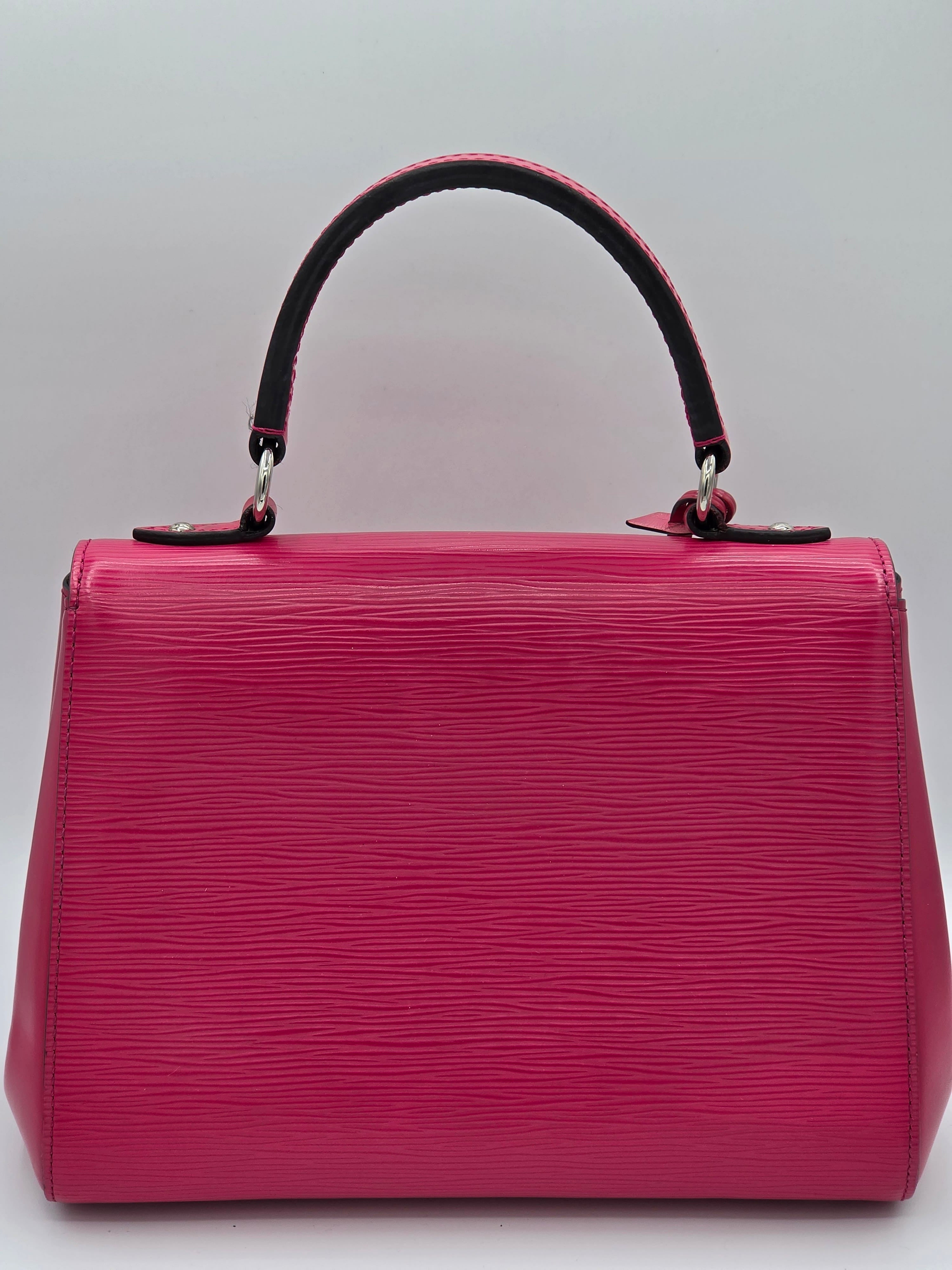 Pink handbag with black handle on a light gray background