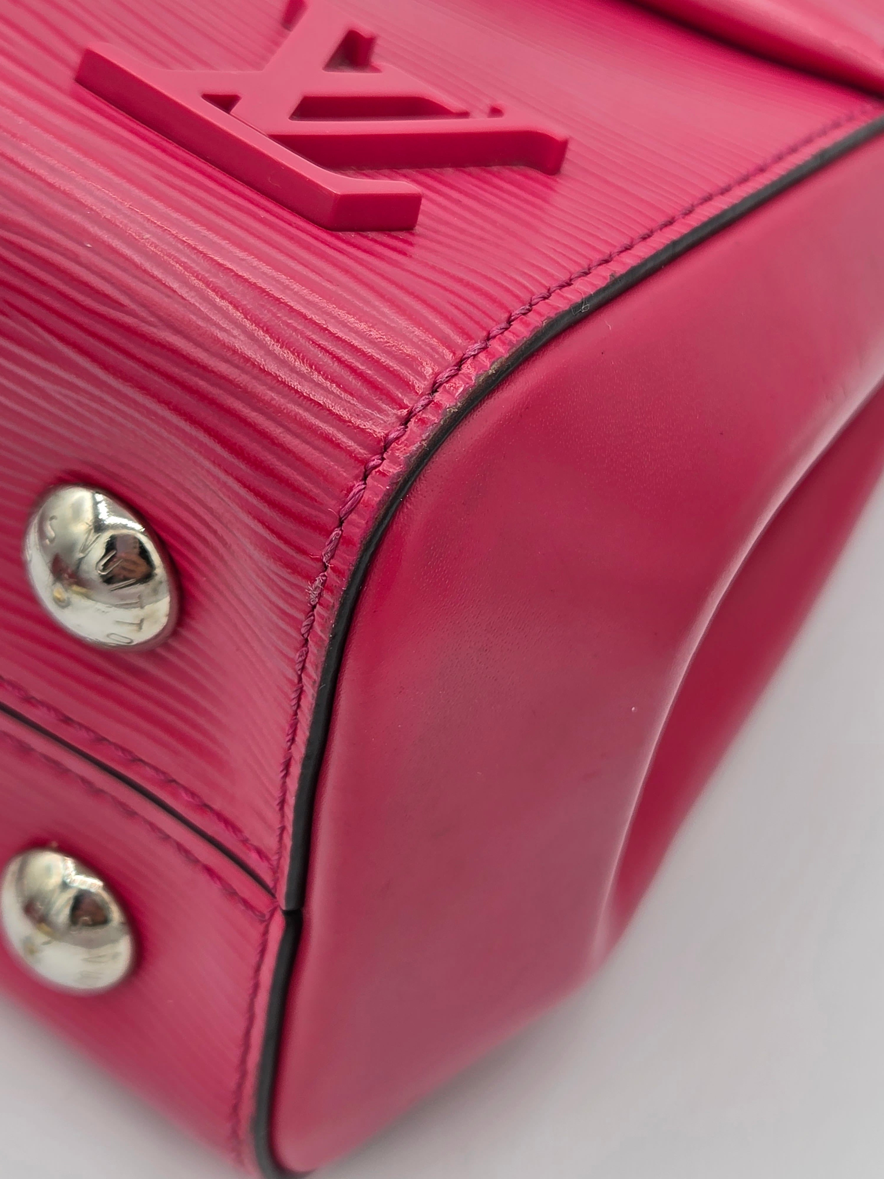 Close-up of a pink handbag with a brand logo and silver studs on a white background