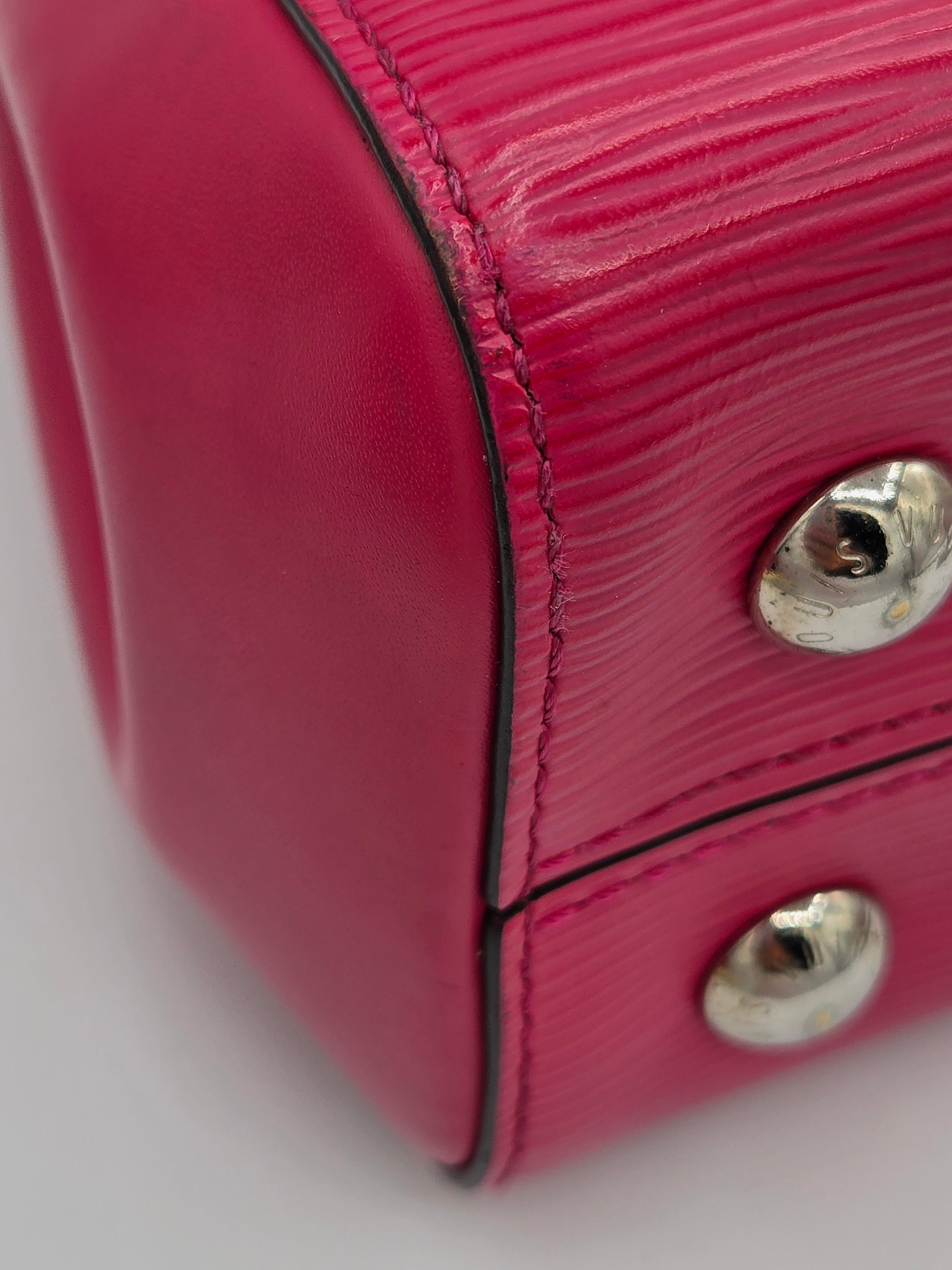 Close-up of a pink textured handbag with metal studs on a white background