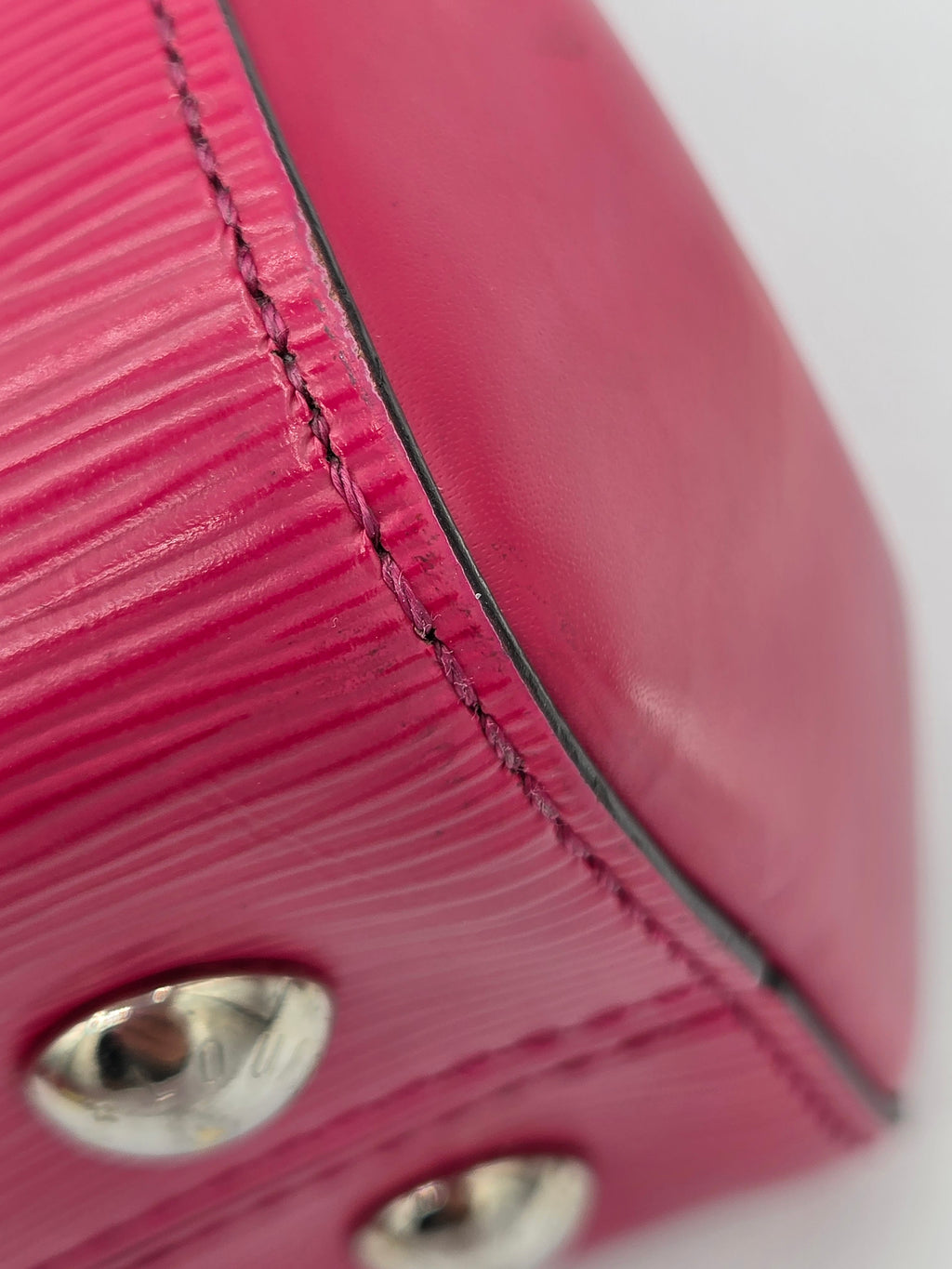Close-up of a pink textured handbag with metal hardware on a white background