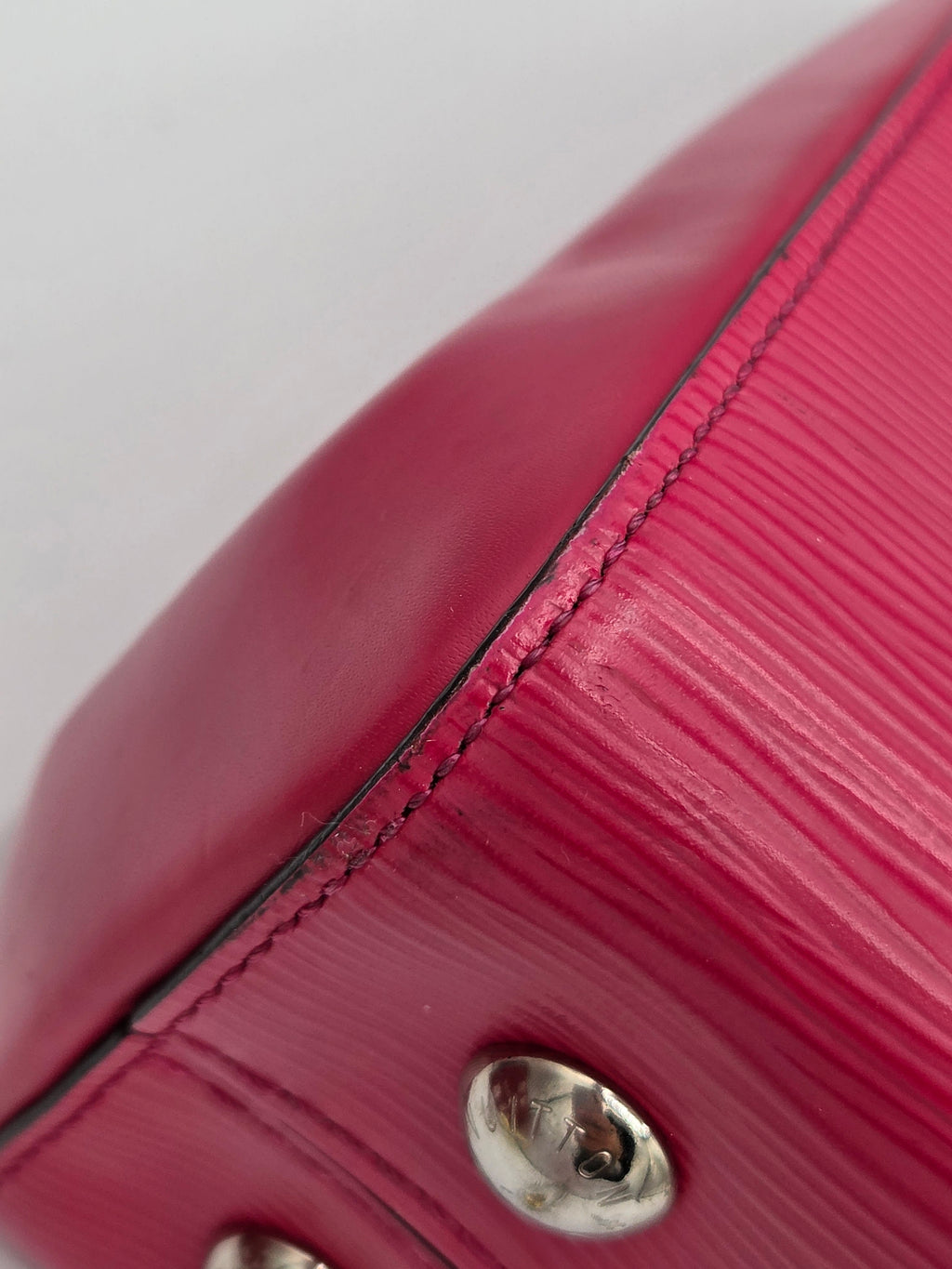 Close-up of a pink textured handbag with a metal clasp on a light gray background