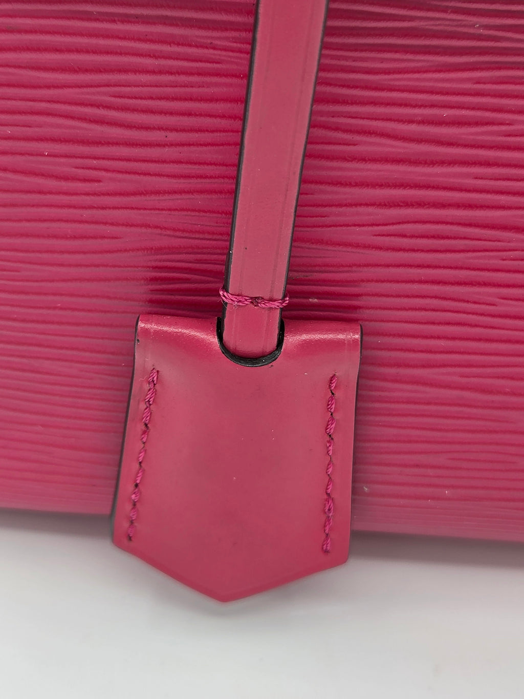 Close-up of a pink textured handbag with a strap on a white background