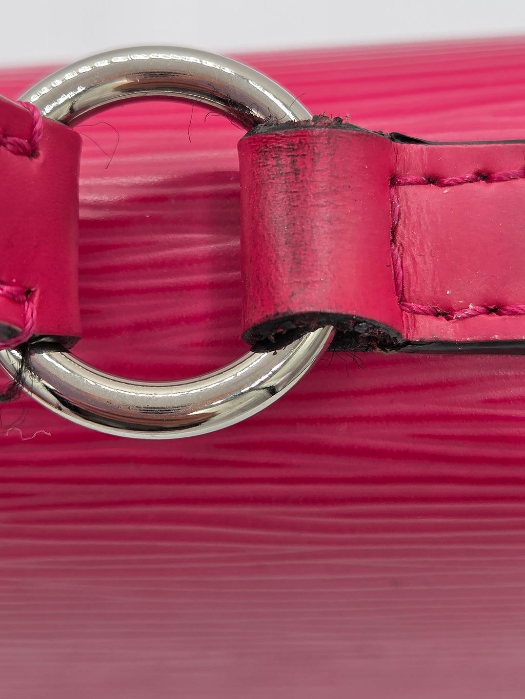 Close-up of a pink leather dog collar with a silver ring on a pink background