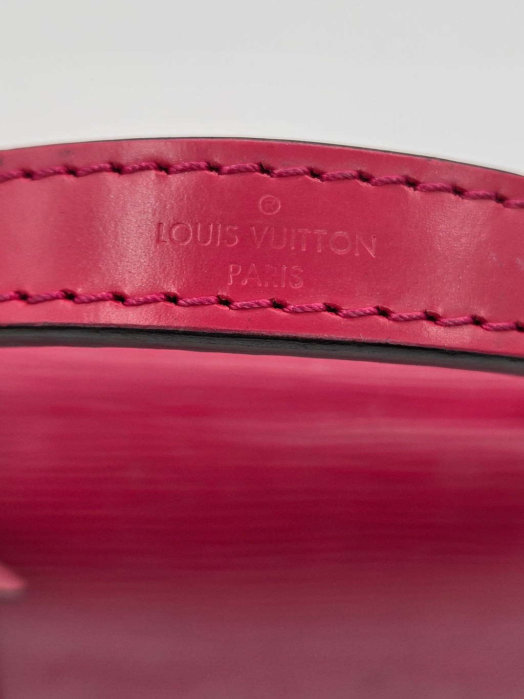 Close-up of a red leather product with 'Louis Vuitton' branding.