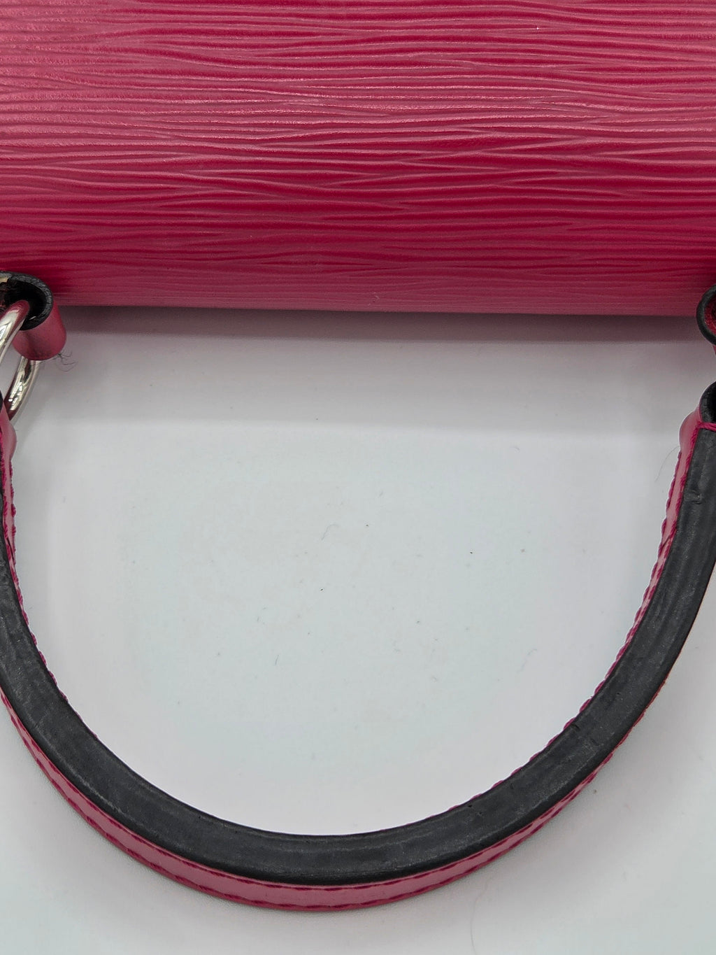 Close-up of a pink textured handbag handle on a light gray background