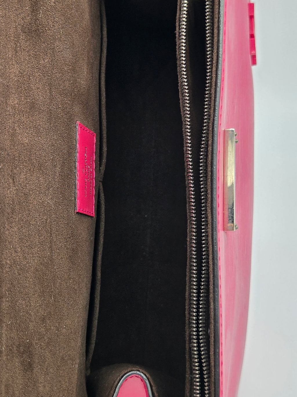 Close-up of a pink and black suitcase with a visible brand label.