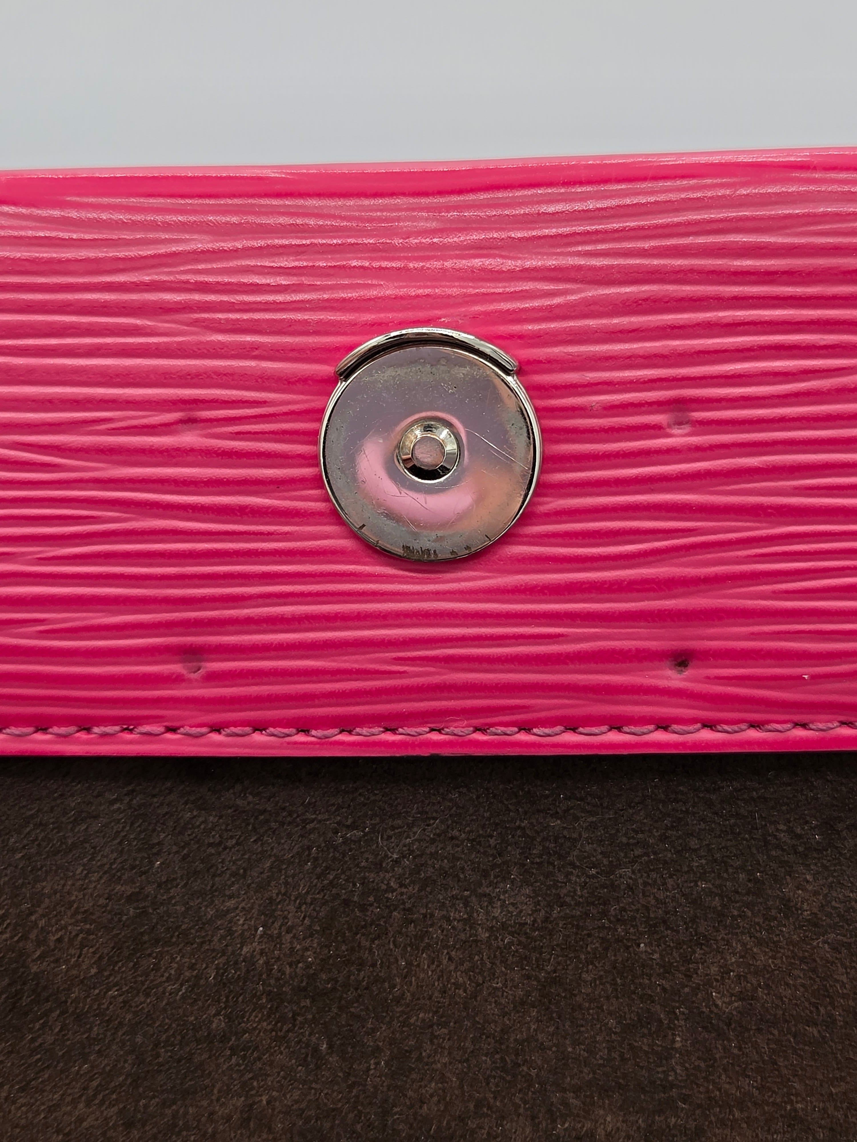 Close-up of a pink textured surface with a metal button and brown fabric.