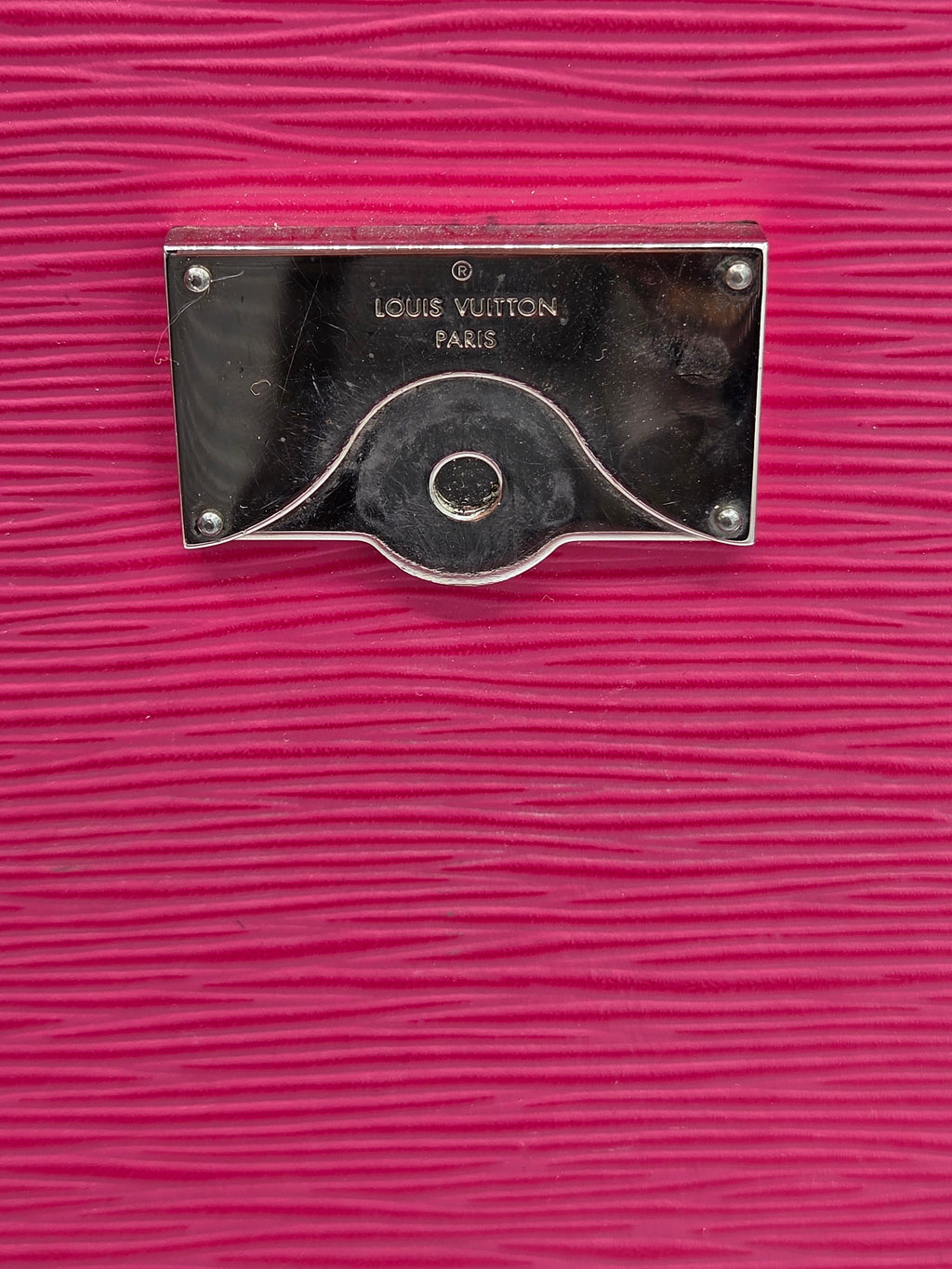 Close-up of a Louis Vuitton handle on a pink textured surface