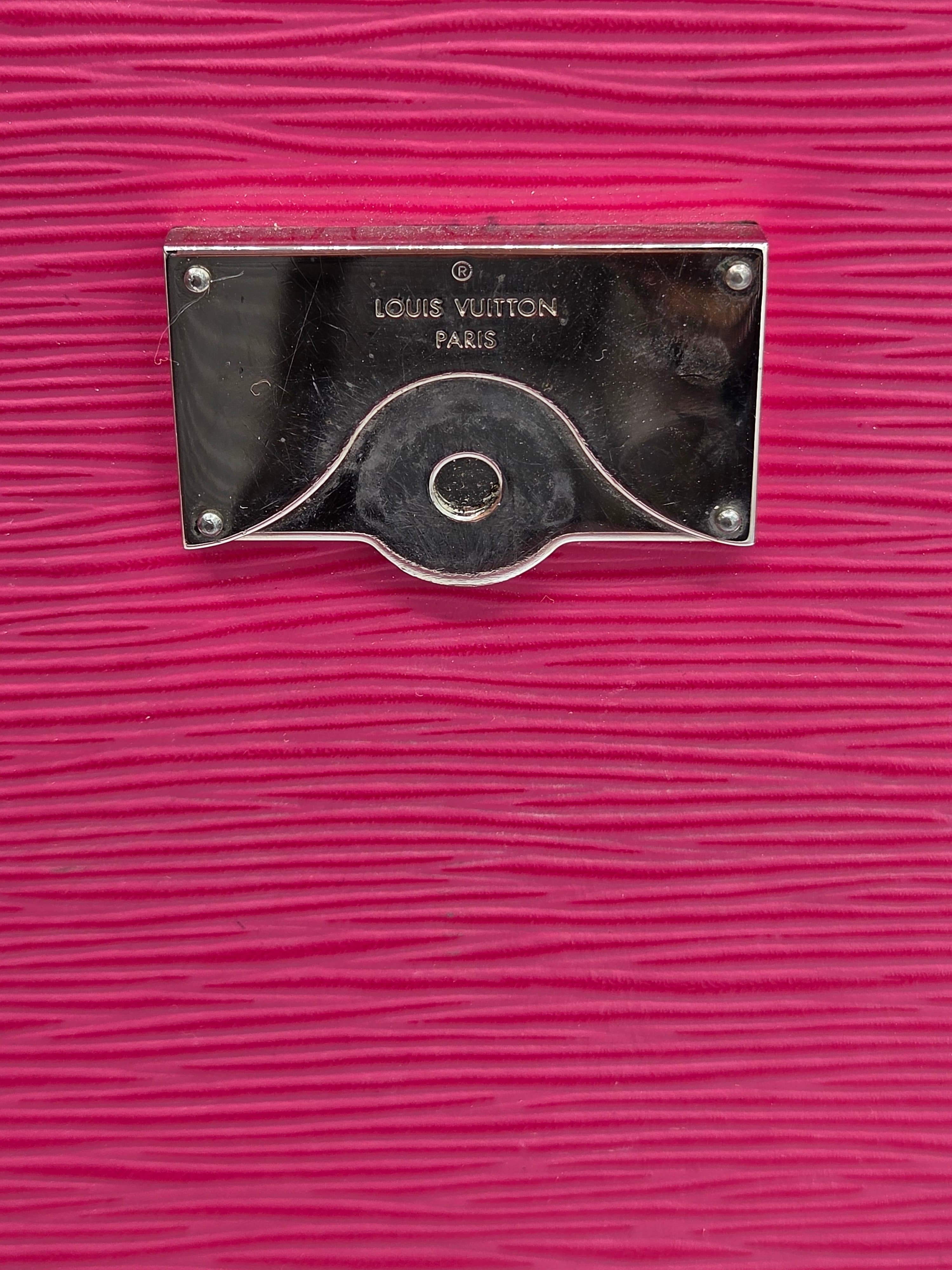 Close-up of a Louis Vuitton handle on a pink textured surface
