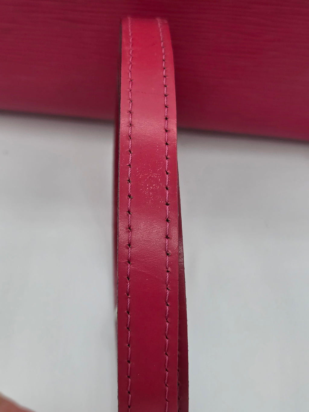 Close-up of a red leather strap with stitching on a white background
