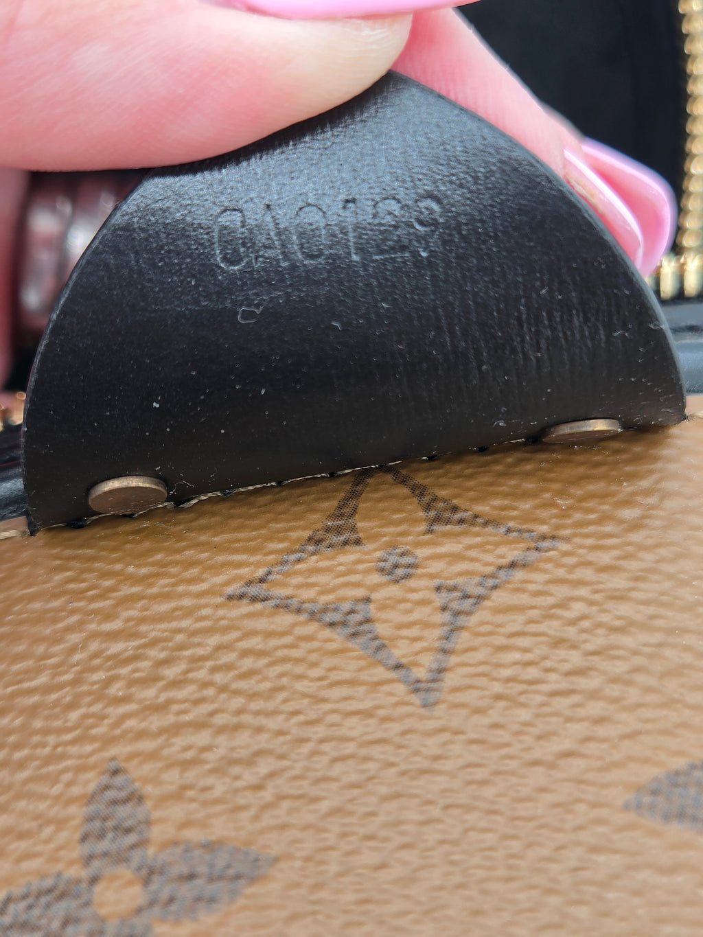 Close-up of a black leather strap with 'Louis Vuitton' branding on a brown leather surface.