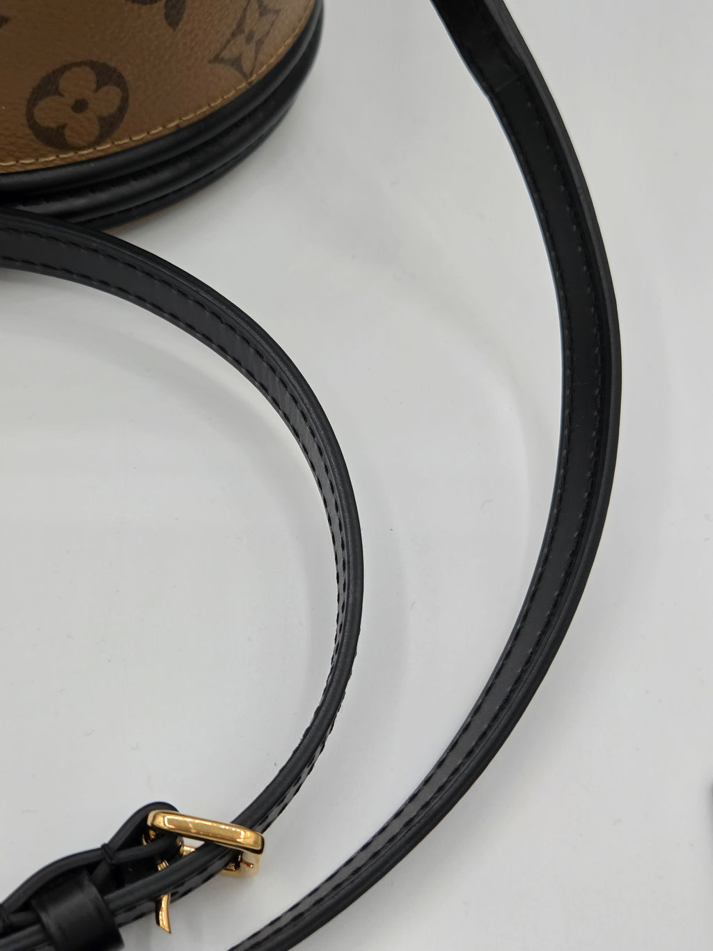 Close-up of a black headphone cord with gold connector on a light gray background