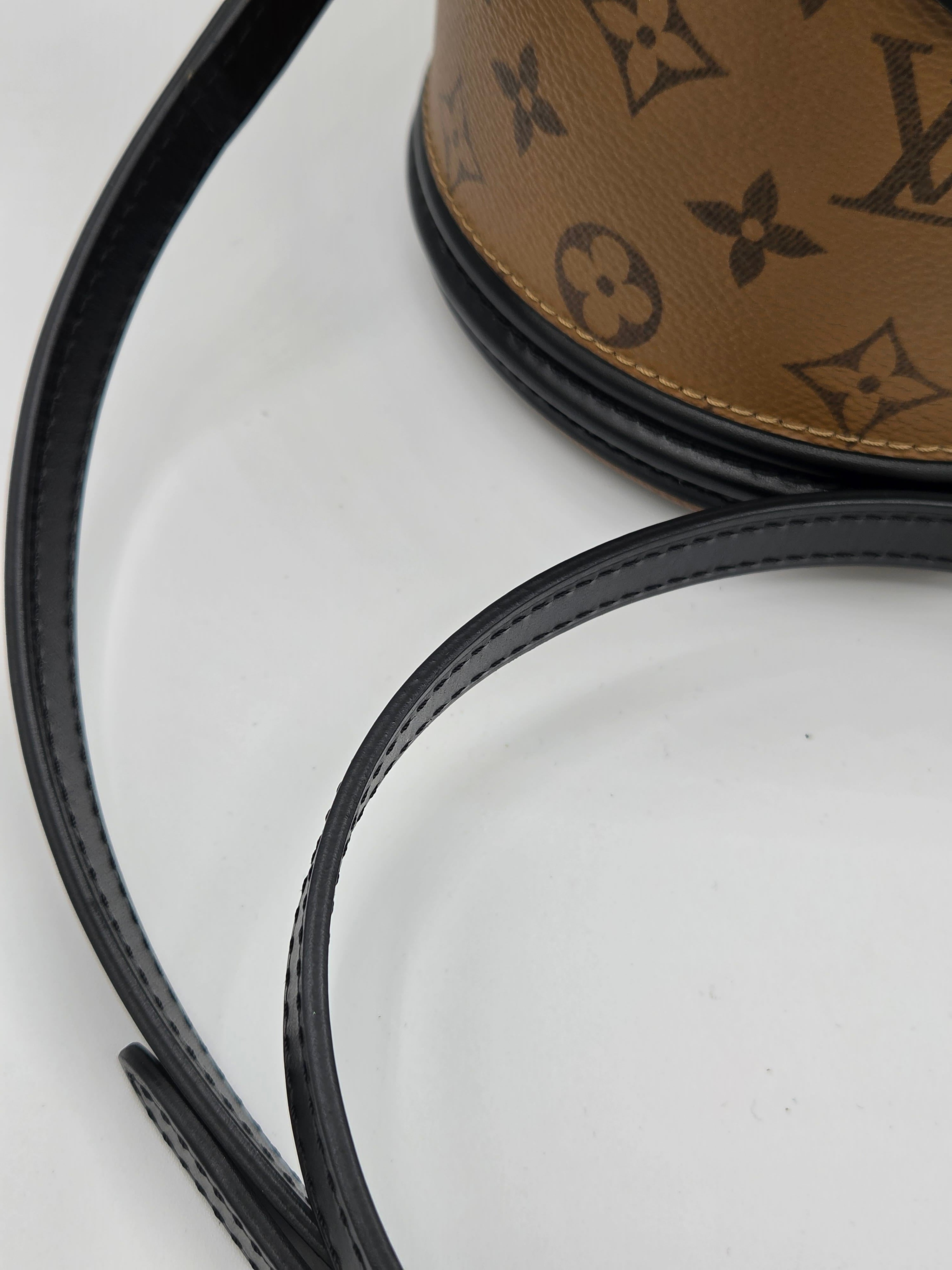 Close-up of a black leather belt with a brown leather patch featuring a logo on a white background