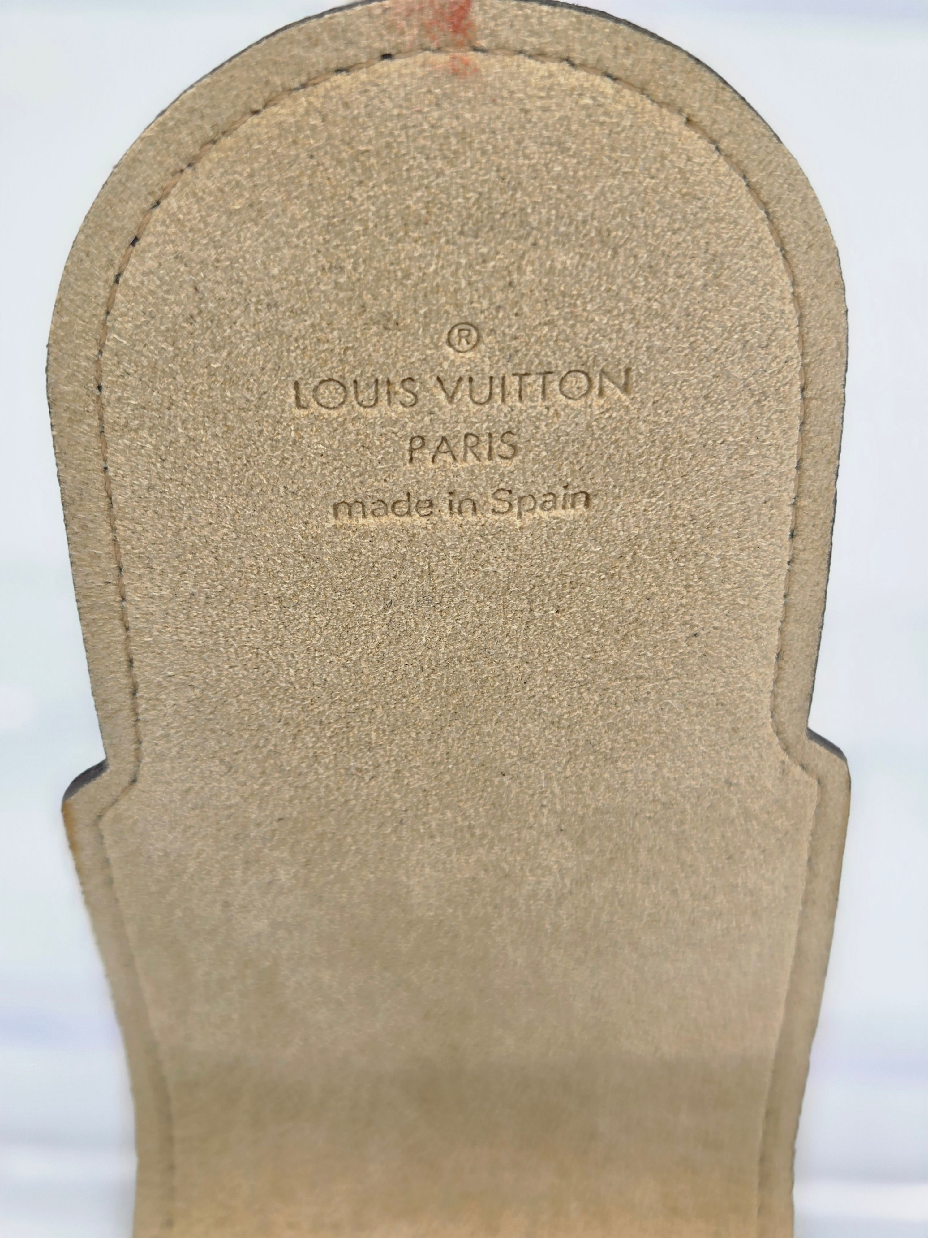 Close-up of a Louis Vuitton sandal insole showing the printed brand name 'LOUIS VUITTON PARIS' and 'made in Spain' on a beige suede-like surface.