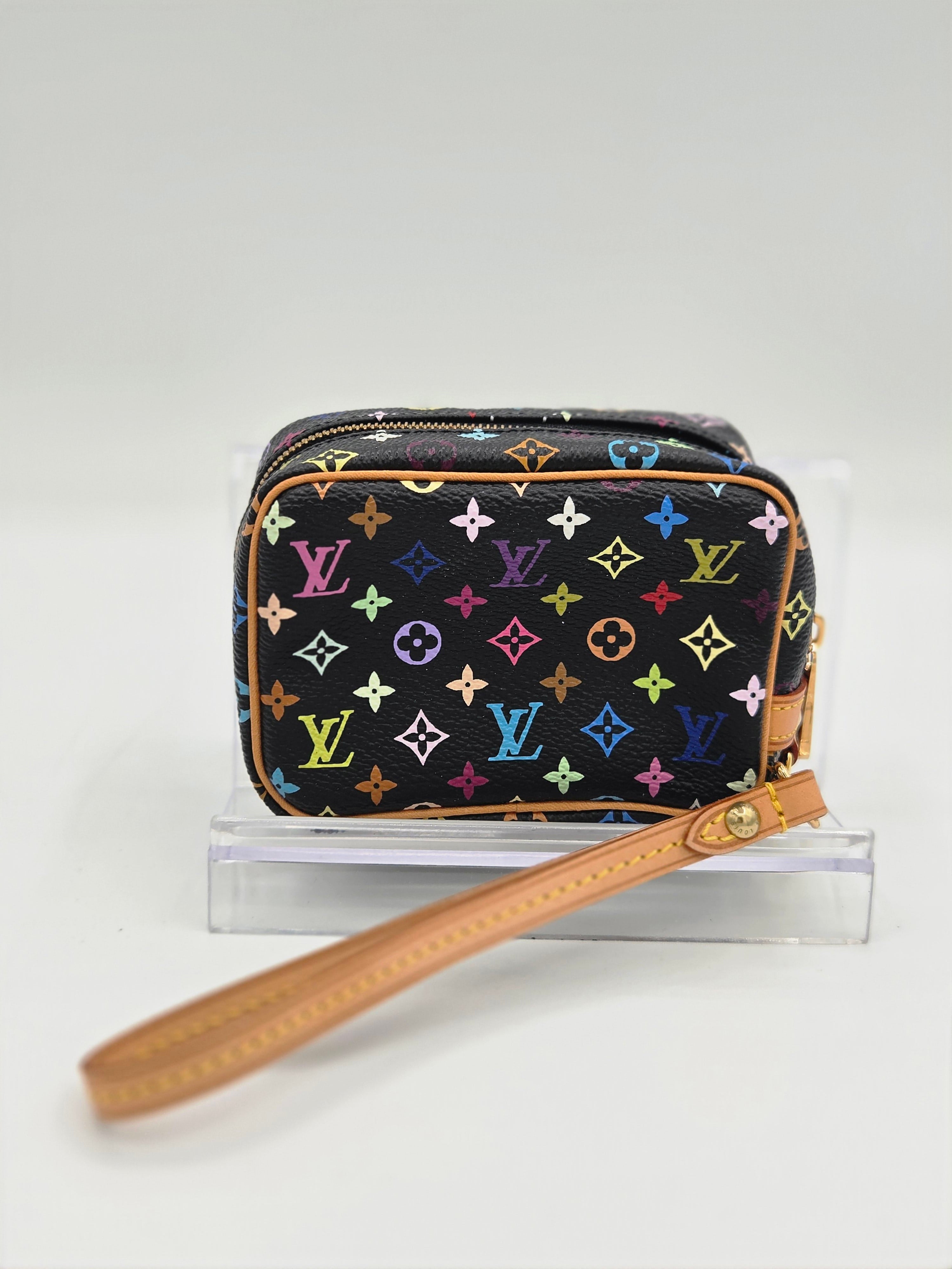 A Louis Vuitton monogram camera bag in black canvas with a colorful multicolor monogram pattern and tan leather wristlet strap, shown hanging from a clear acrylic stand against a white background.