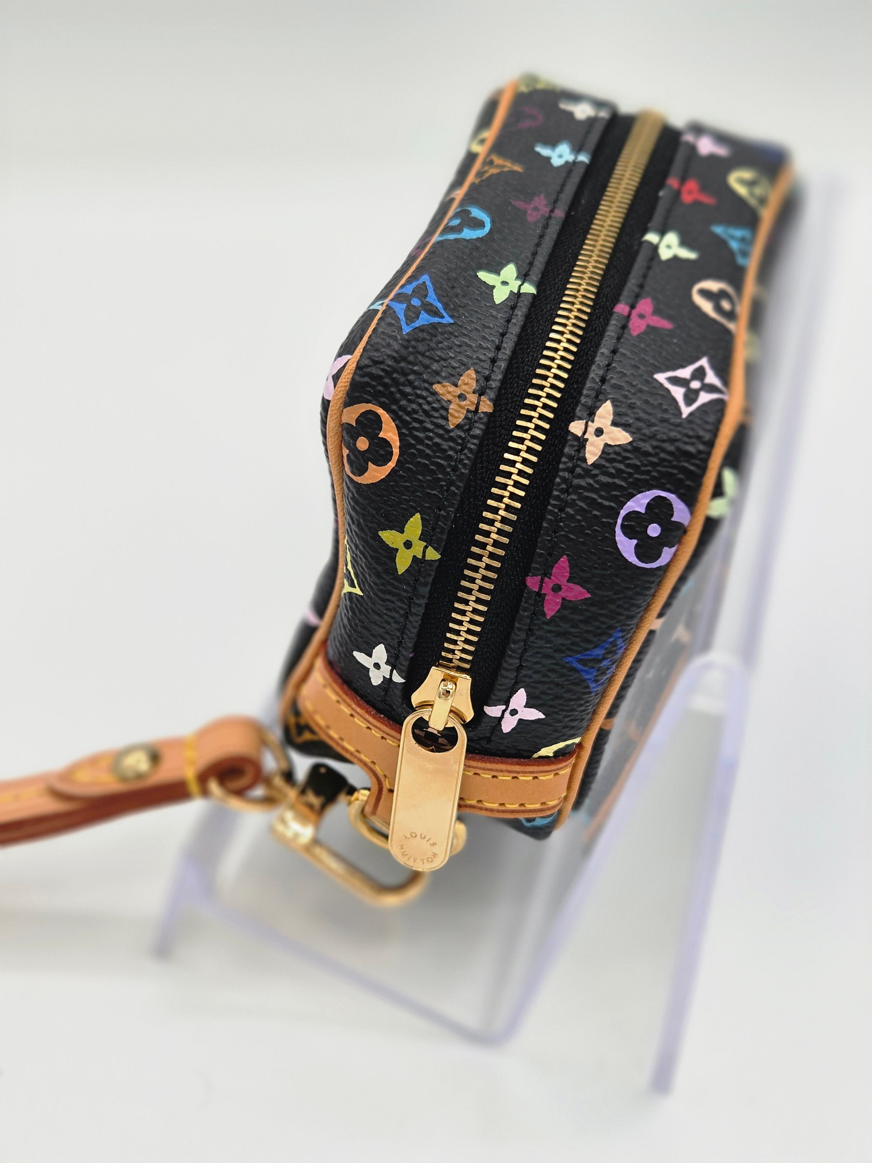 A Louis Vuitton monogram canvas wristlet pouch with a colorful floral print on a black background, featuring gold-tone hardware and tan leather trim, shown on a white background.