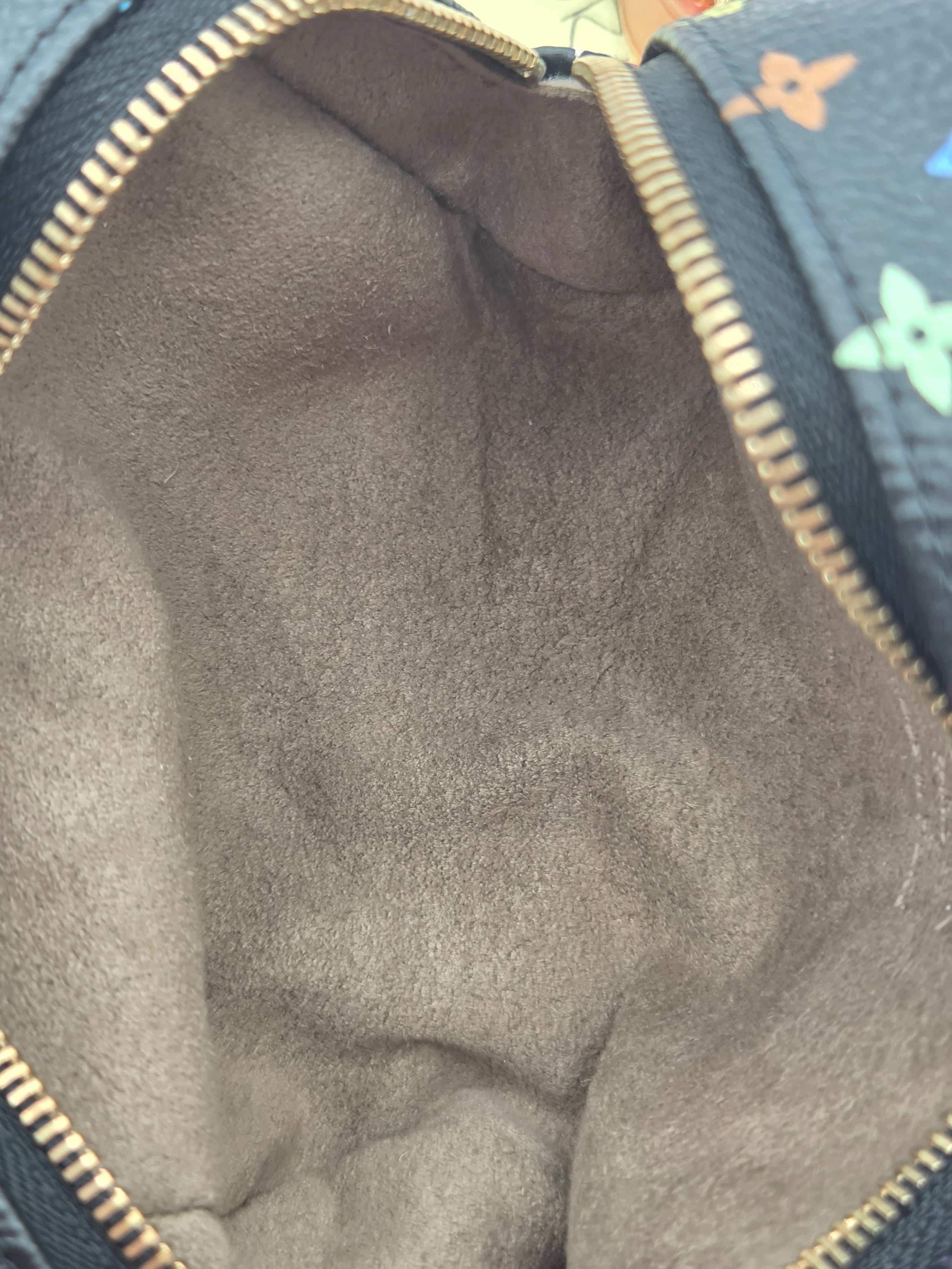 Close-up of the interior lining of a Louis Vuitton bag, showing a dark gray suede or microfiber lining with a gold-tone zipper and a portion of the classic multicolor monogram canvas at the top.