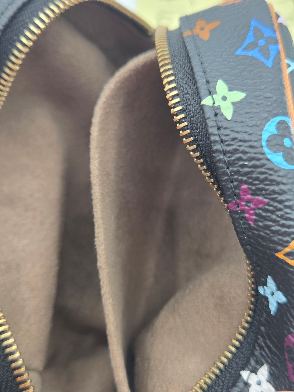 Close-up of a Louis Vuitton cosmetic pouch showing the interior lining and a colorful monogram pattern on the exterior.