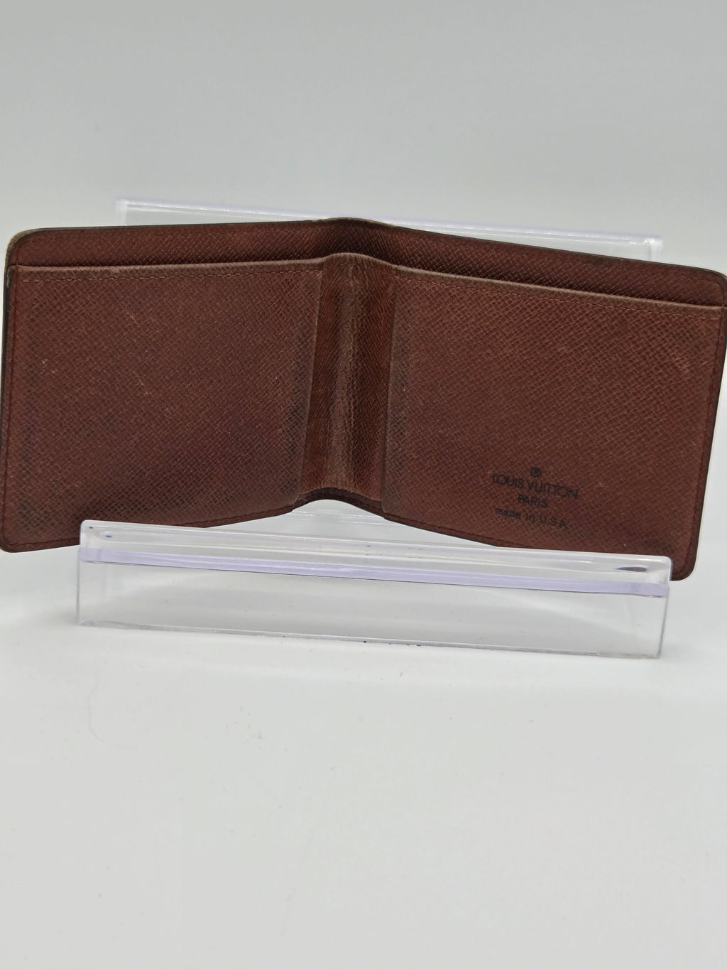 A brown textured leather bifold wallet shown open, positioned vertically against a plain white background.