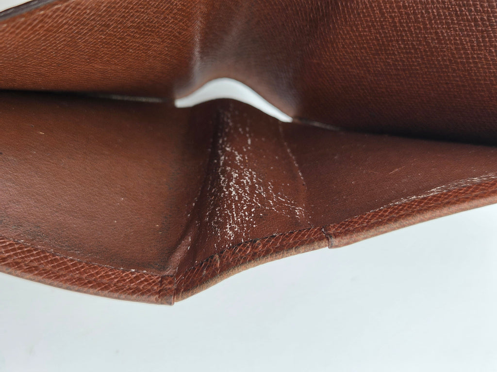 Close-up of a brown textured leather interior corner with visible wear, scuffing, and dust particles on the surface.