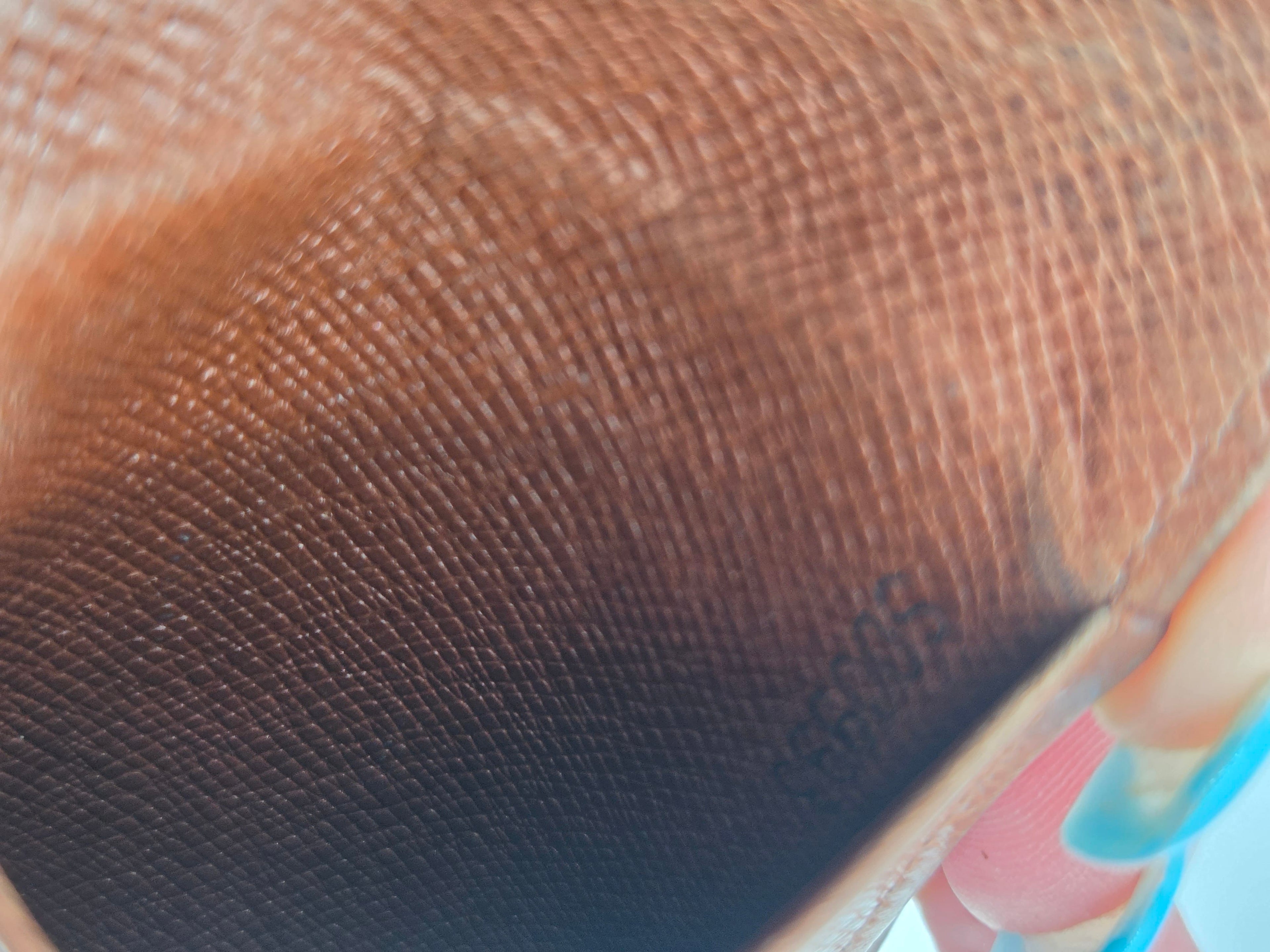 Close-up of a brown textured material with a fine woven or mesh-like pattern, partially folded over with a small light-colored edge visible.