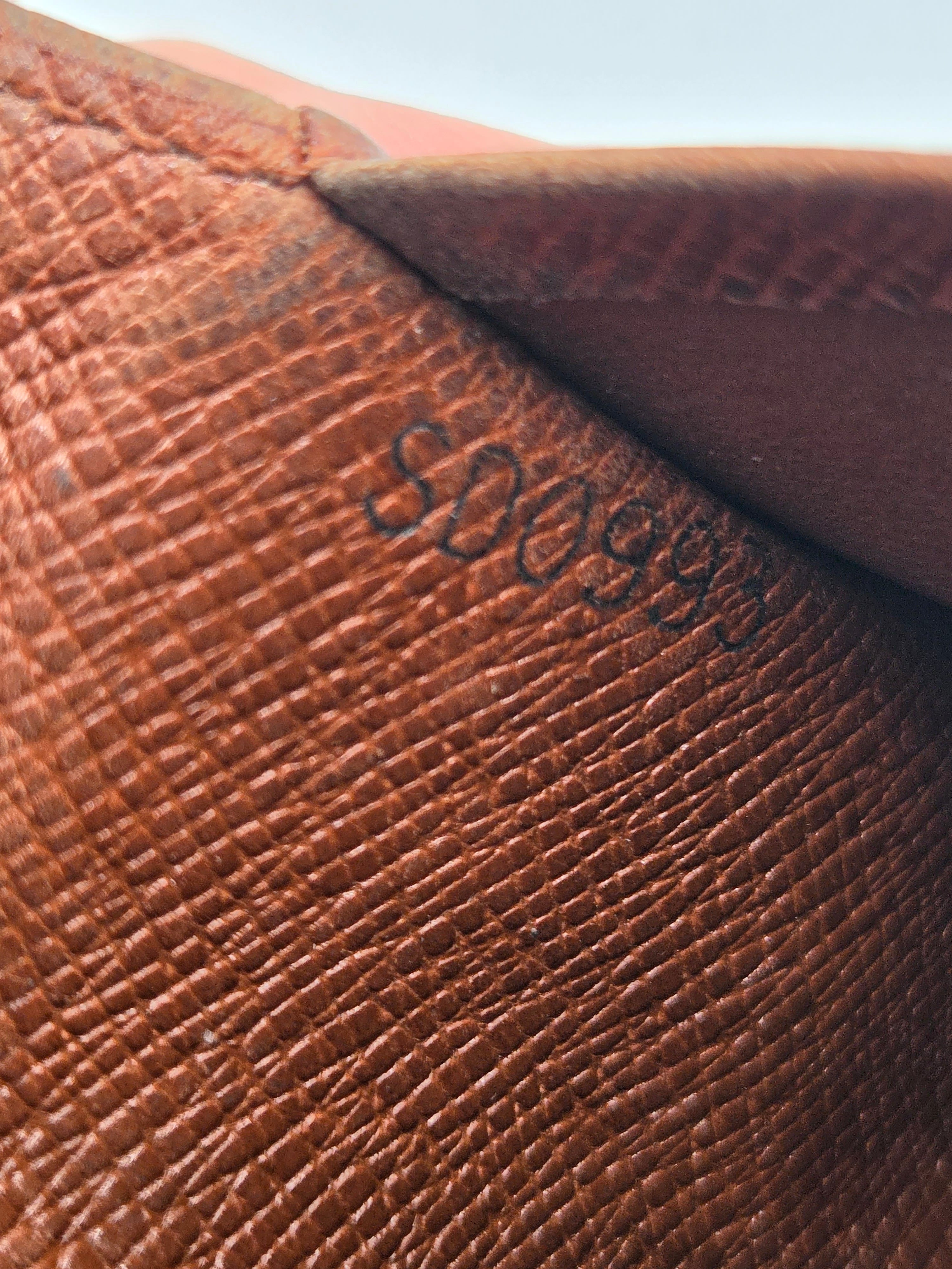 Close-up of a brown textured leather surface with embossed black numbering and a folded corner showing a darker brown interior.