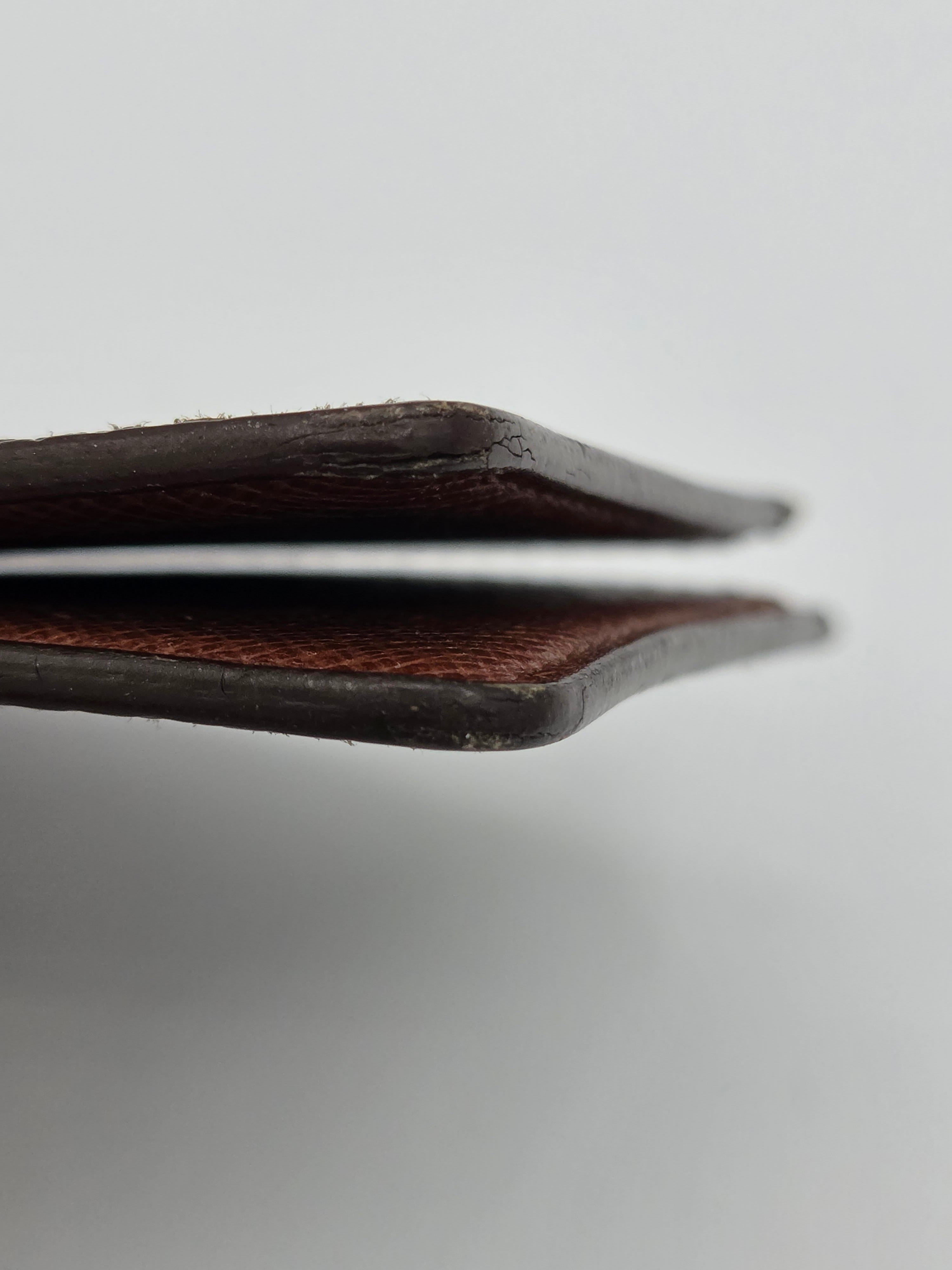 Close-up of the side profile of a dark brown leather wallet or card holder, showing the textured leather edge against a light gray background.