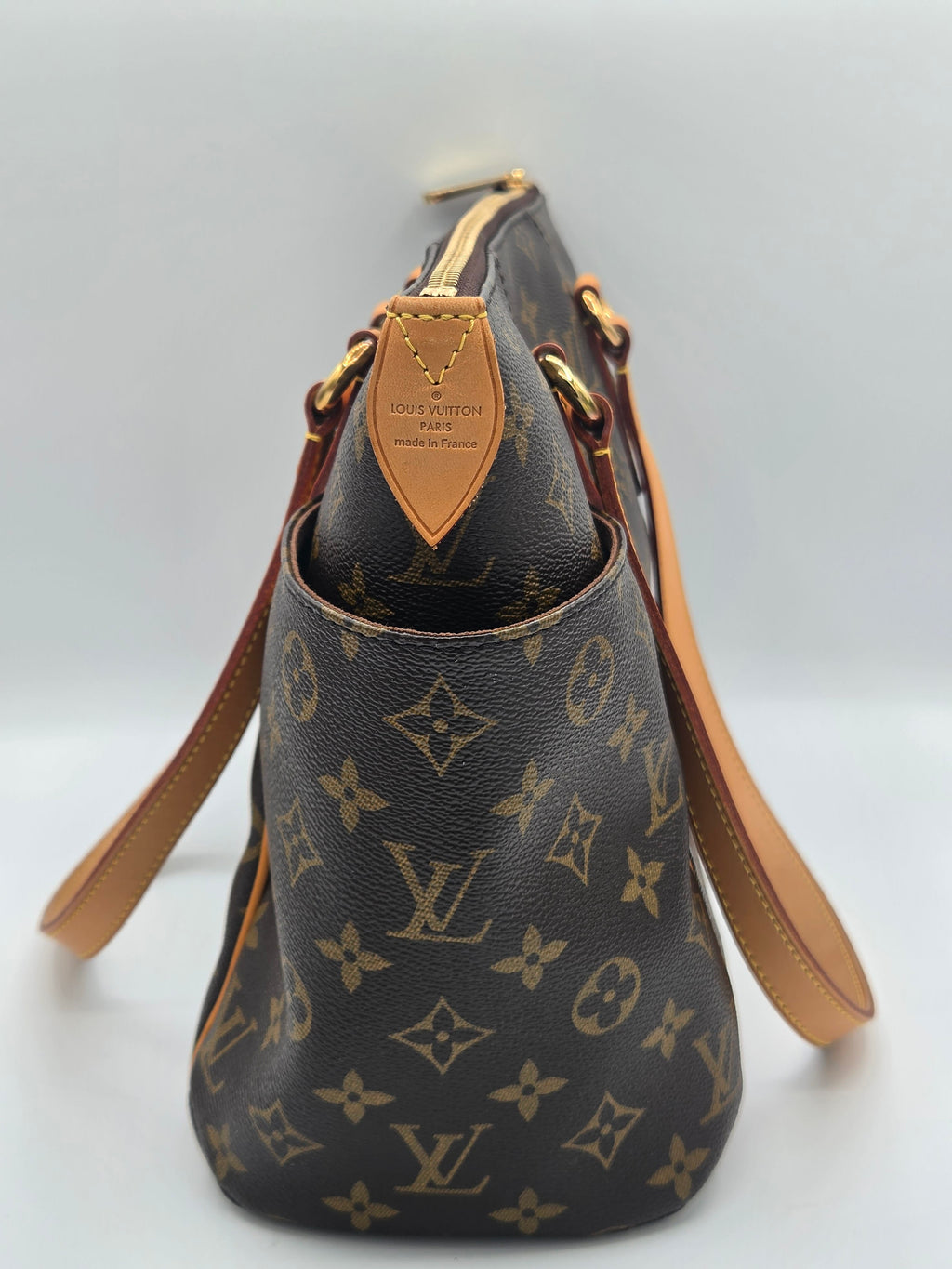 Louis Vuitton monogram canvas shoulder bag in dark brown with tan leather trim and straps, shown on a light gray background.