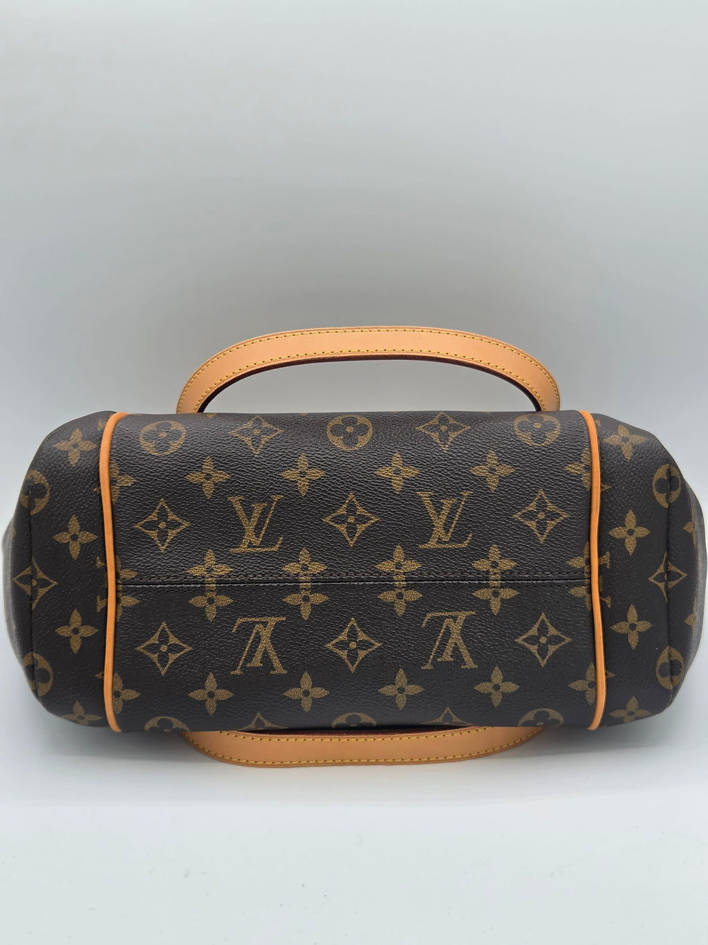 Louis Vuitton monogram canvas shoulder bag in dark brown with tan leather handles and trim, shown from a top-down view on a light gray background.
