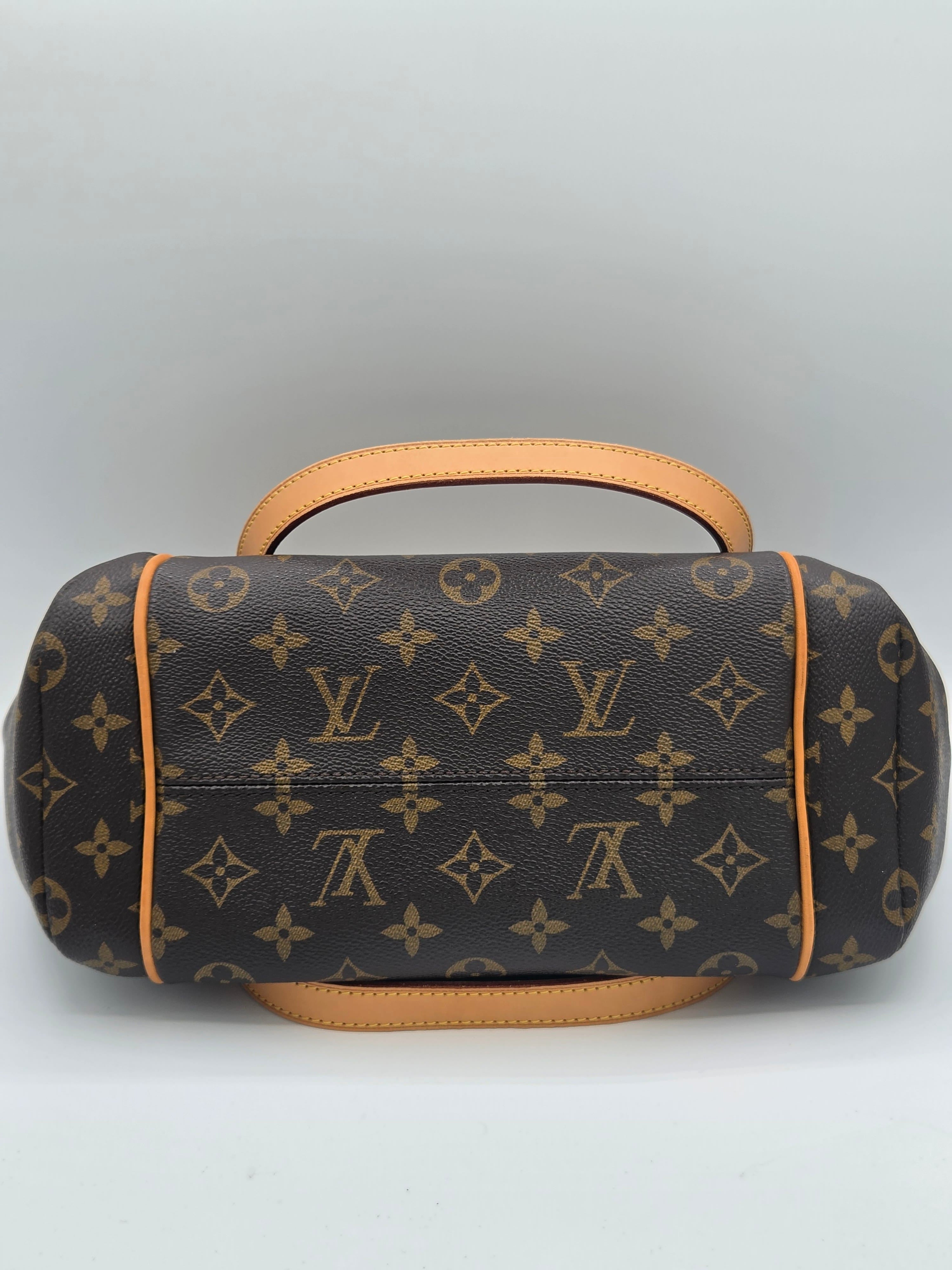 Louis Vuitton monogram canvas shoulder bag in dark brown with tan leather handles and trim, shown from a top-down view on a light gray background.