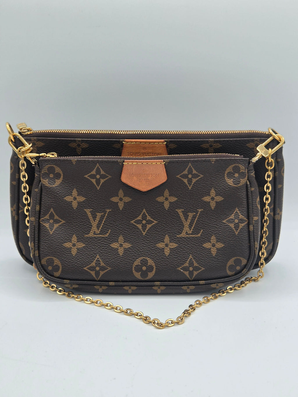 Louis Vuitton monogram canvas shoulder bag with gold-tone chain strap and gold hardware, photographed against a neutral light gray background.