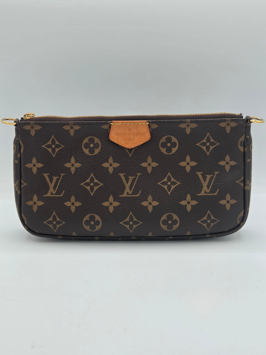 A Louis Vuitton monogram zip-around pouch in dark brown coated canvas with tan leather trim and gold-tone hardware, shown against a light gray background.