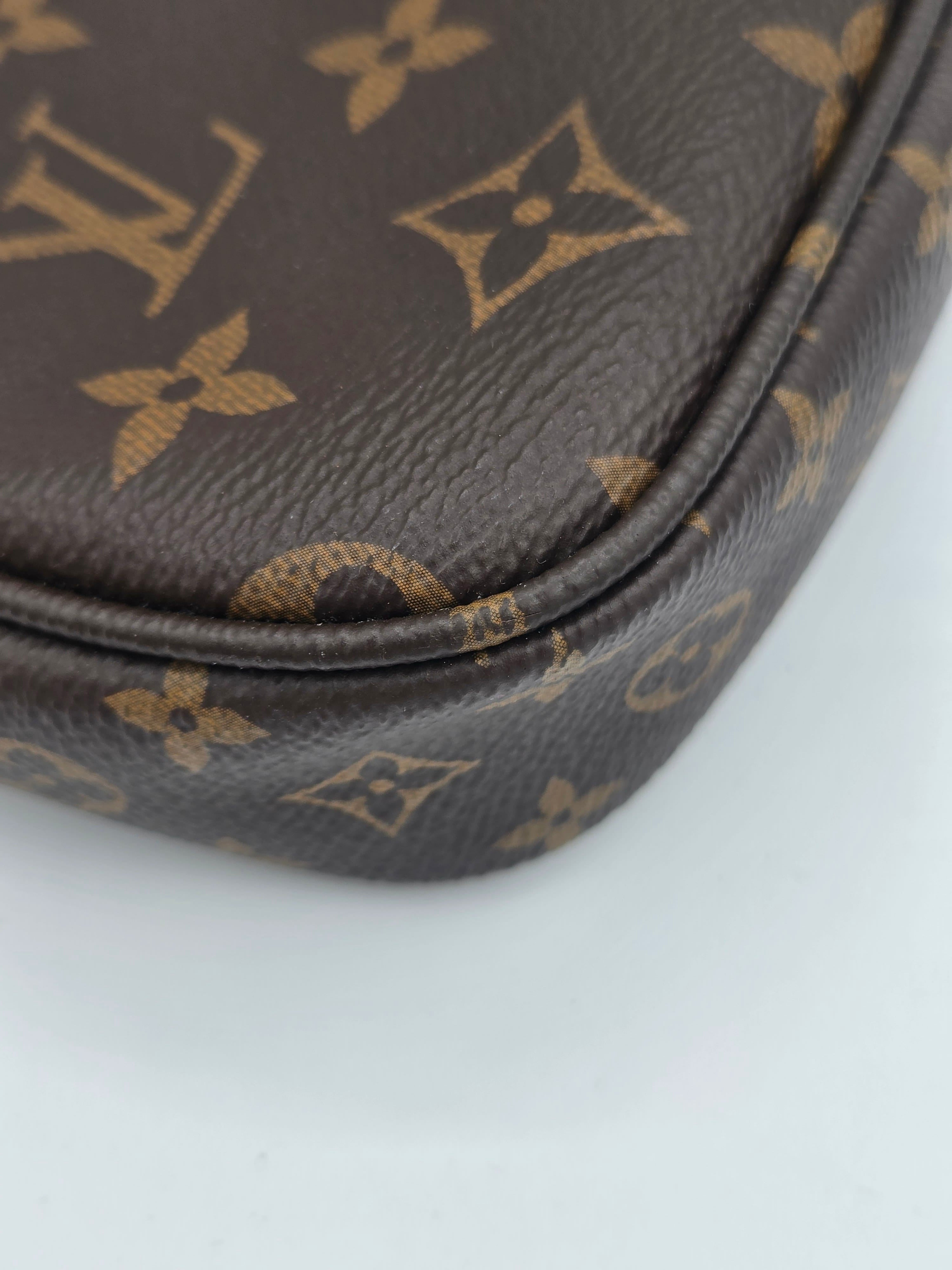 Close-up of a brown coated canvas item featuring the classic tan Louis Vuitton monogram pattern, showing the textured leather grain and a curved seam against a plain light background.