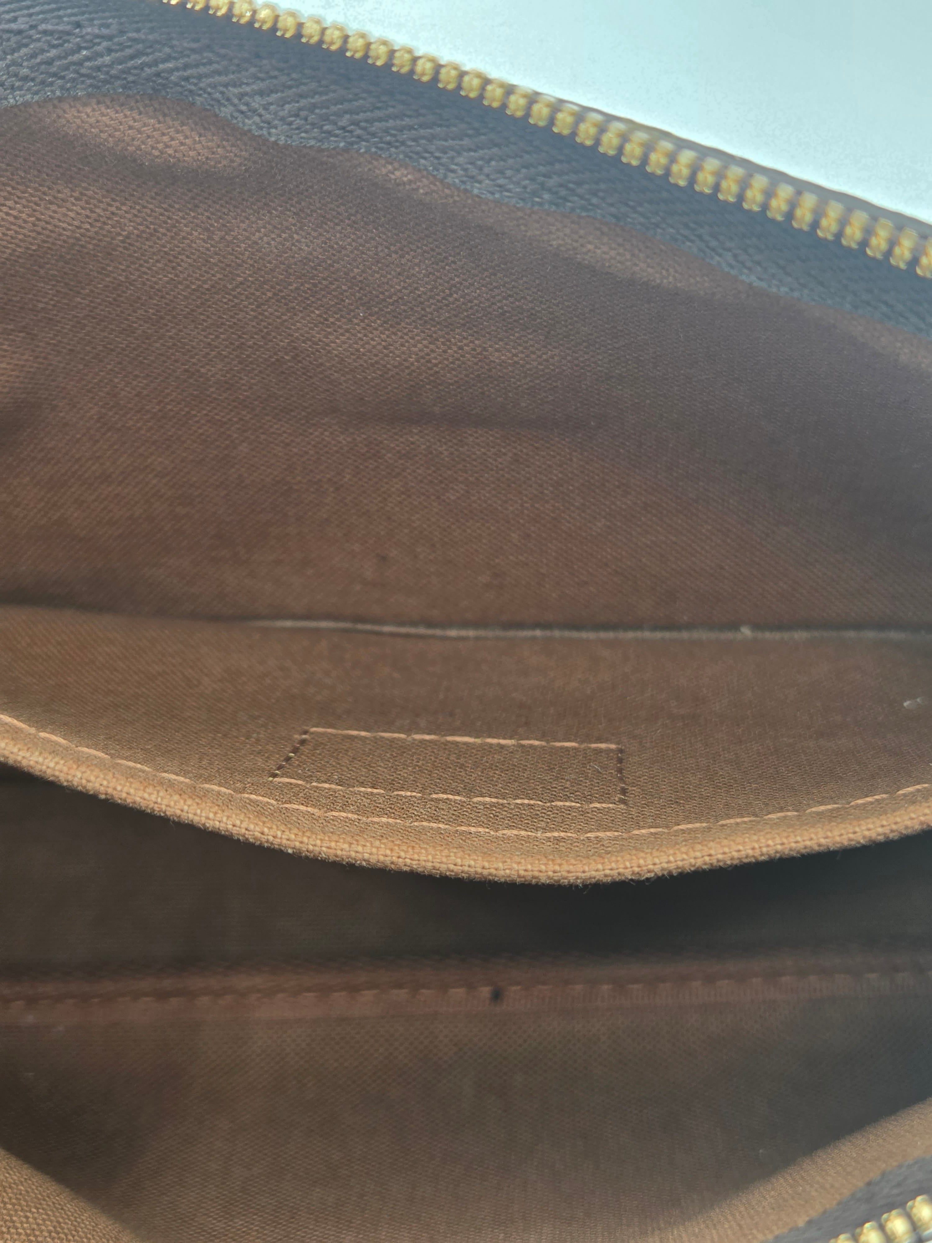 Close-up of the interior lining of a brown canvas bag, showing the tan fabric interior, a stitched pocket edge, and a gold zipper on the left side.