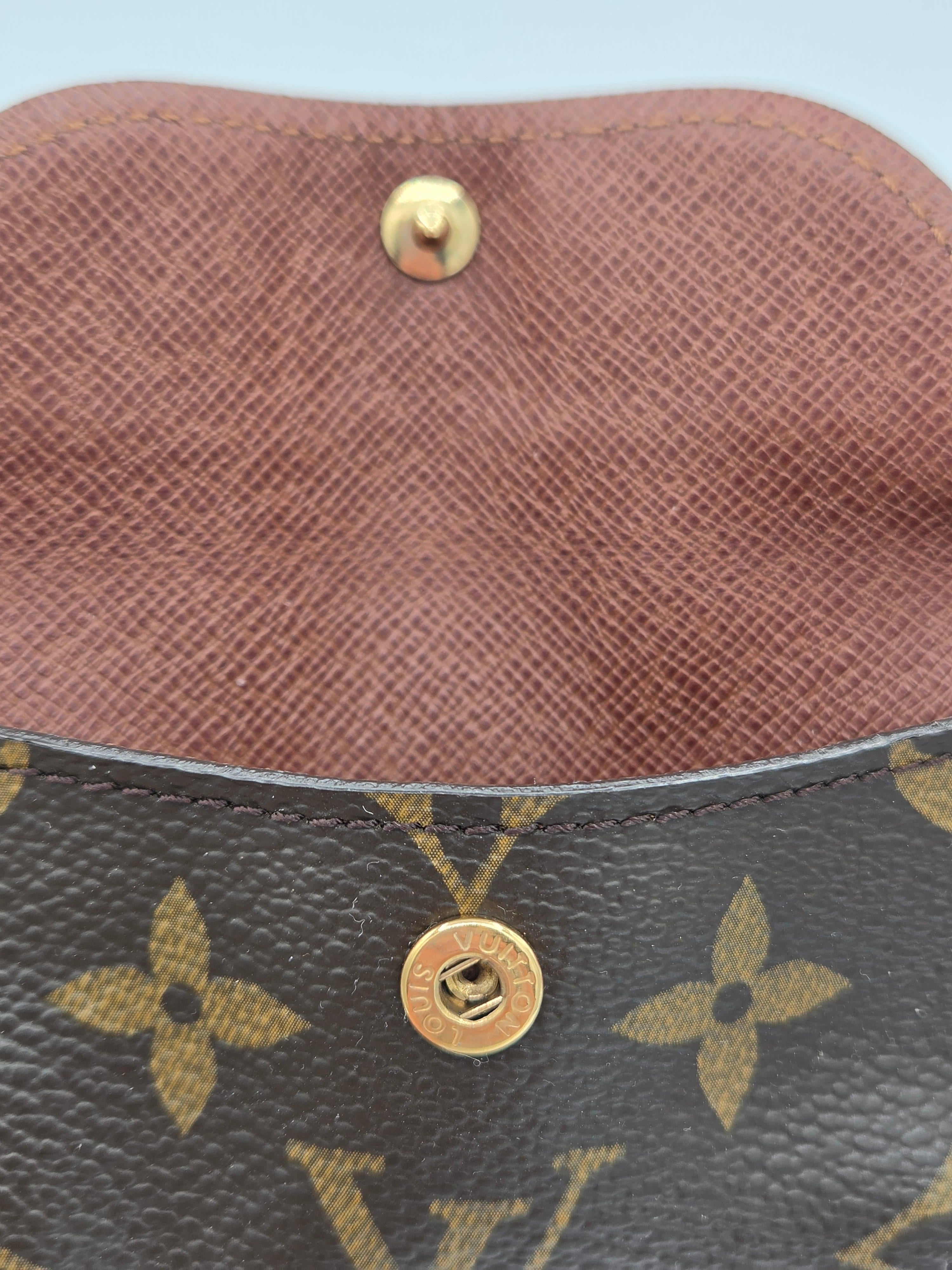 Close-up of a Louis Vuitton monogram bag showing the dark brown coated canvas with gold-tone floral motifs, a brown leather interior lining, and a gold snap button closure.
