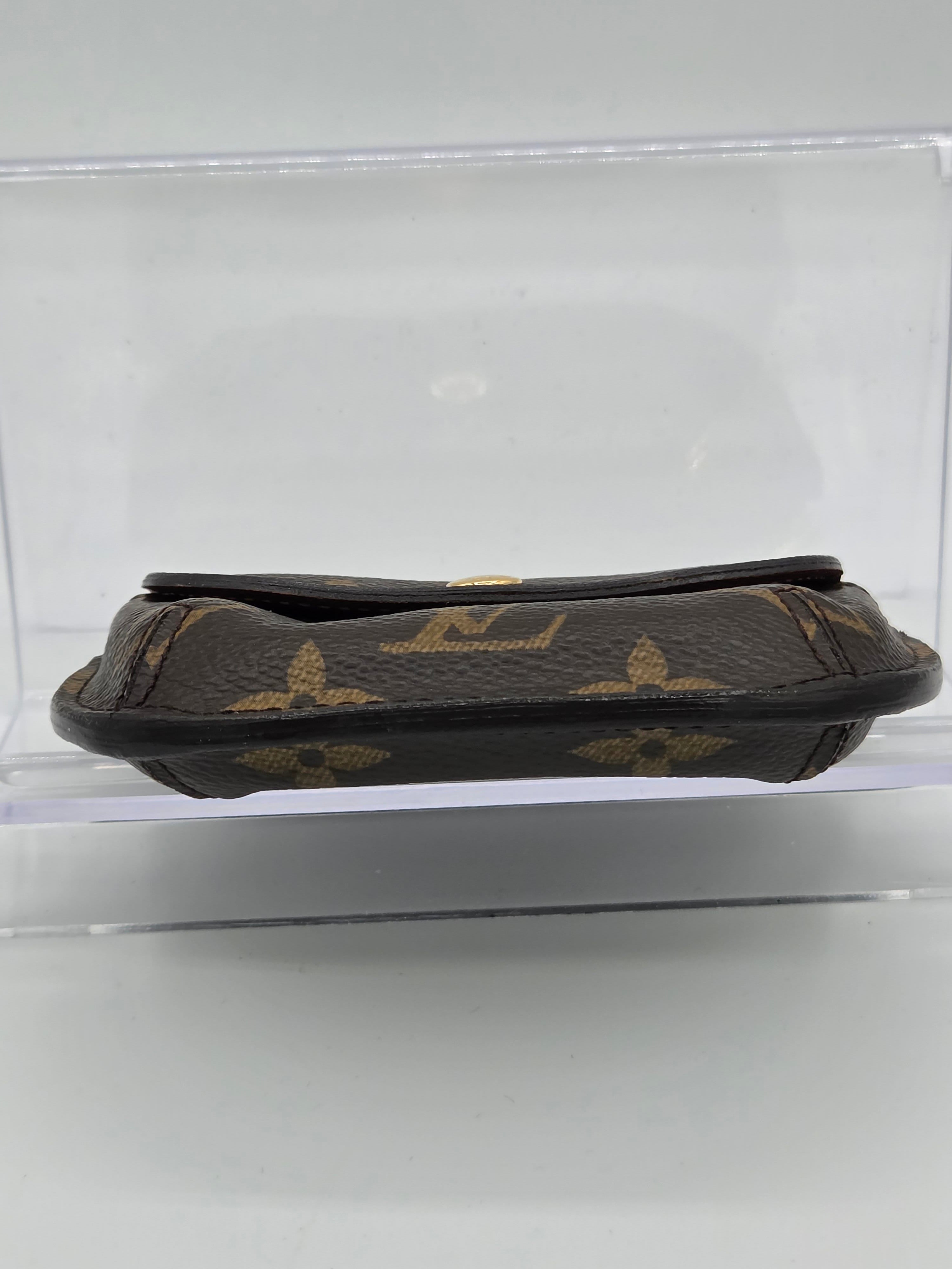 A Louis Vuitton monogram canvas pouch shown vertically inside a clear plastic display case against a white background.