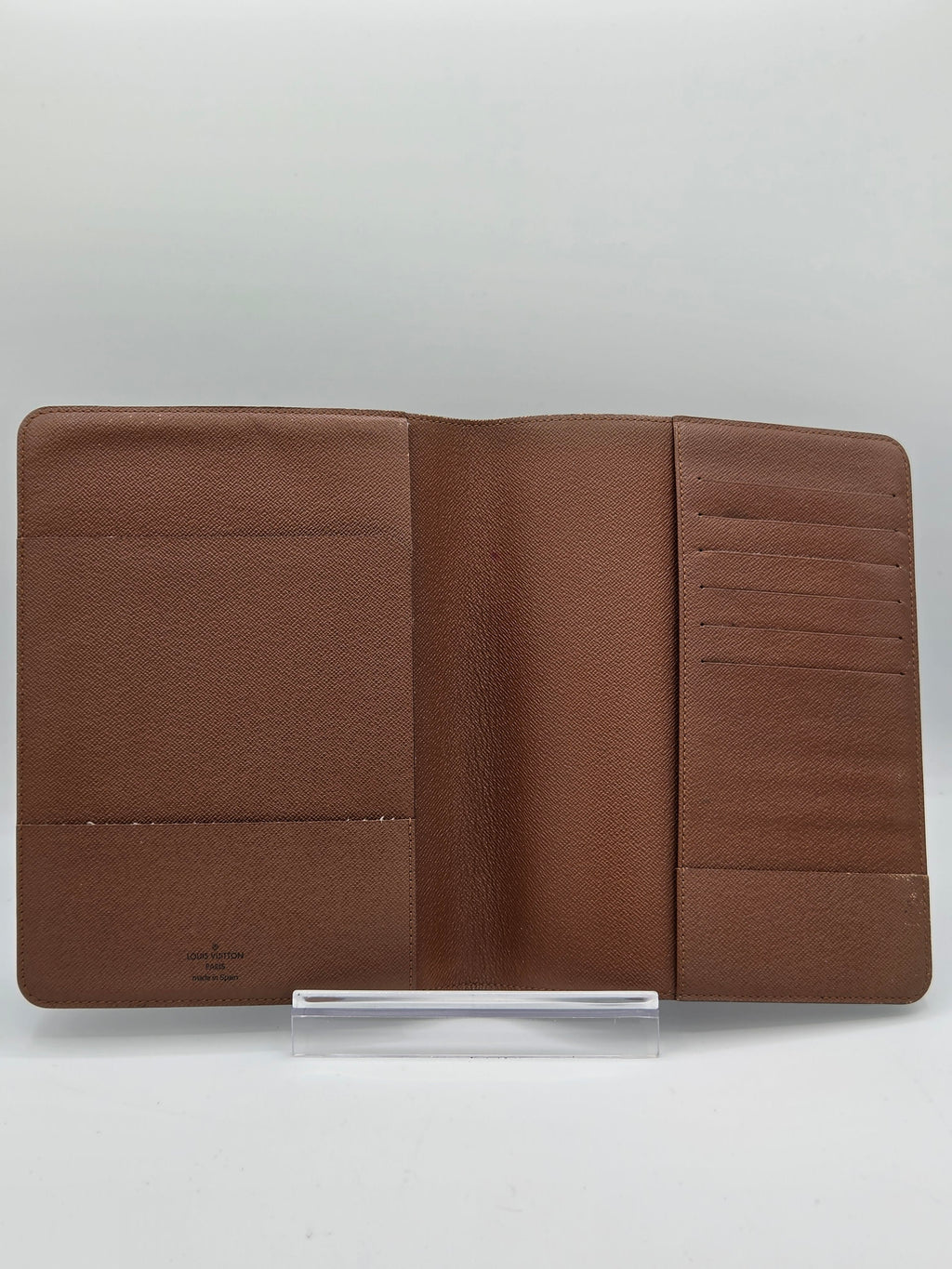 A brown leather wallet shown open, displaying its interior card slots and pocket compartments, photographed against a light gray background.