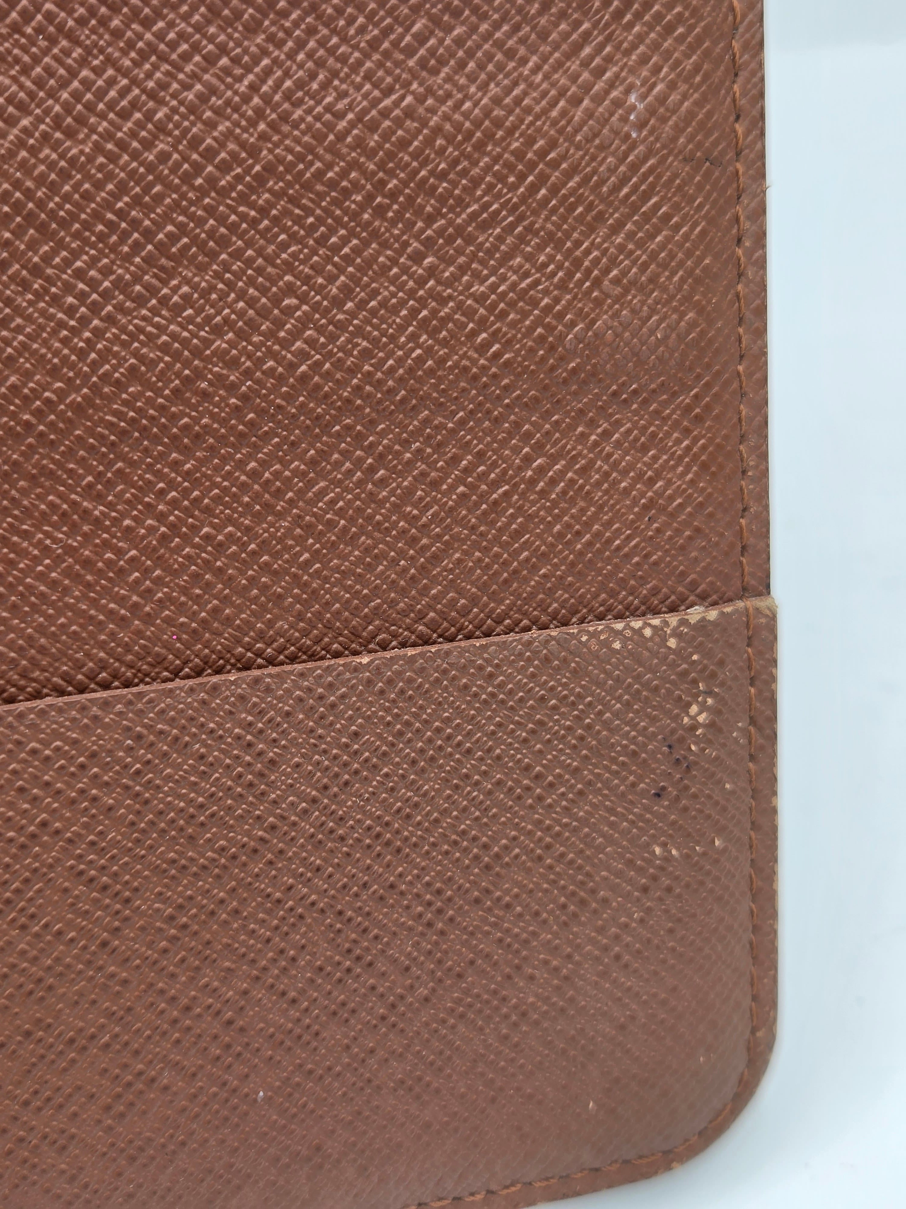 Close-up of a brown textured leather or faux-leather item, showing a fine grain pattern and a vertical seam with some dust or lint visible on the right side.